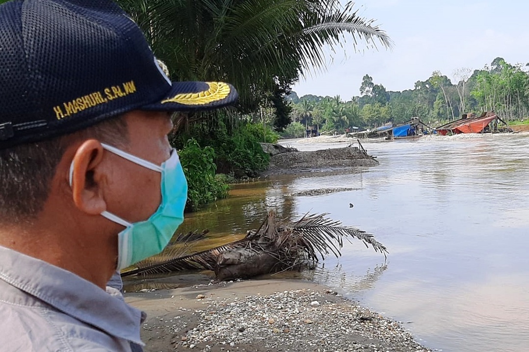 Plt Bupati Merangin, Jambi H. Mashuri berdiri risau di pinggir Sungai Batang Tabir, memandangi aktivitas penambangan emas tanpa izin.