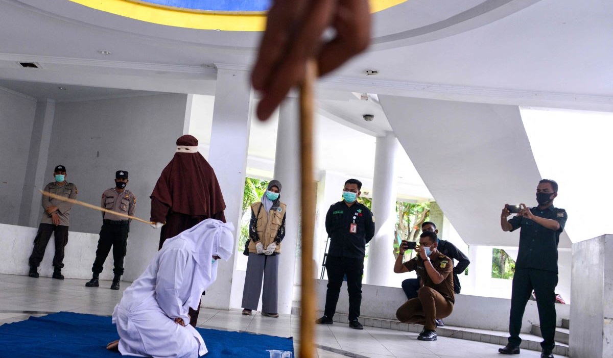 Seorang wanita (tengah) dicambuk di depan umum oleh polisi syariah sebagai hukuman berdasarkan hukum syariah Aceh.