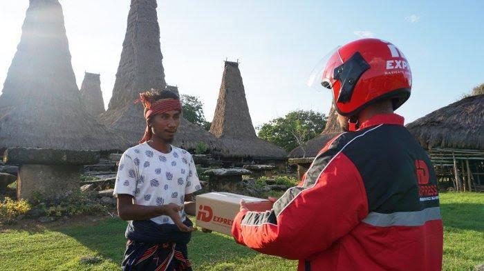 Seorang kurir iDexpress menyerahkan paket kepada pelanggan 