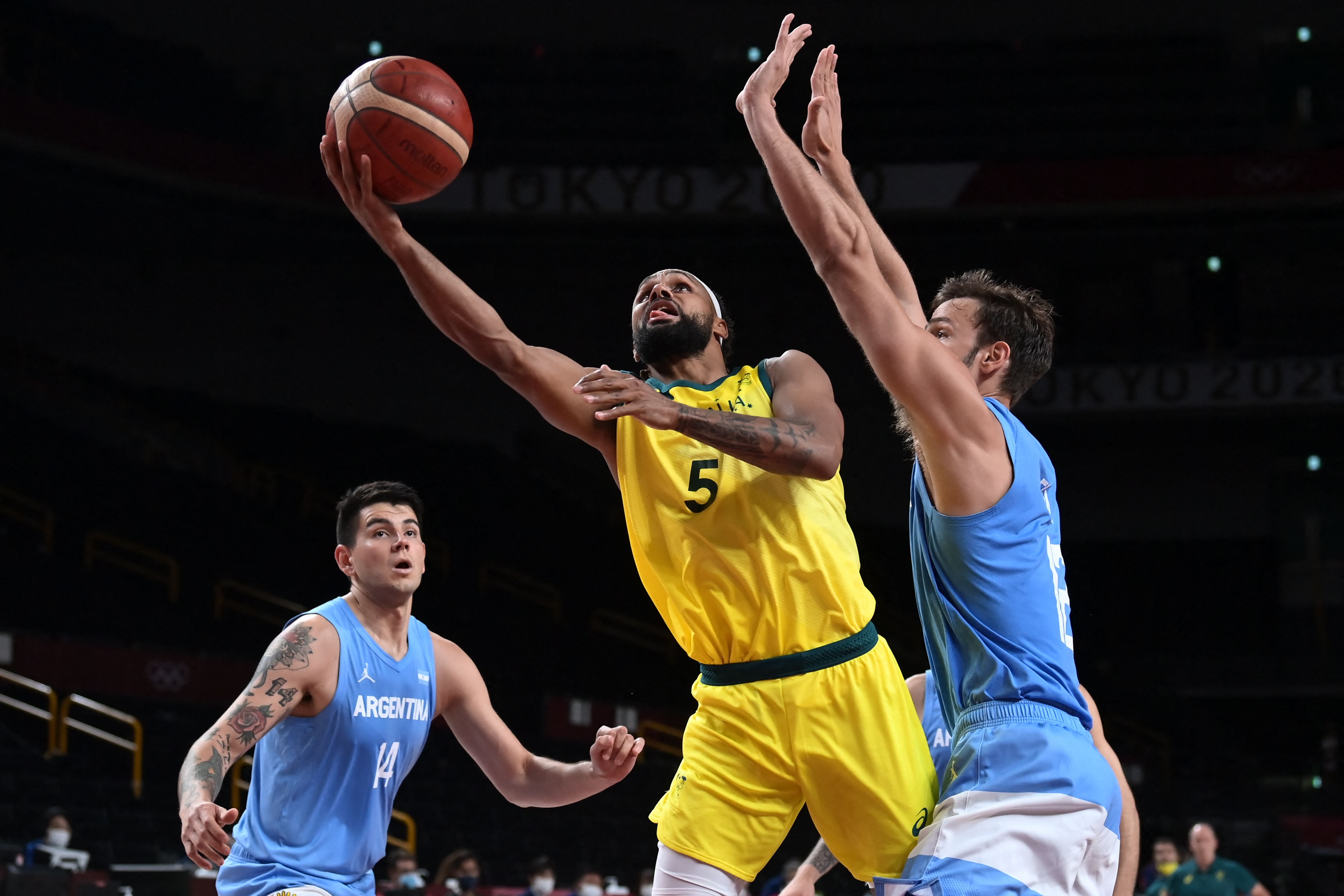 Kapten Timnas basket Australia Patty Mills (tengah) ingin melewati pebasket Argetina Marcos Delia pada laga perempat final Olimpiade Tokyo. 