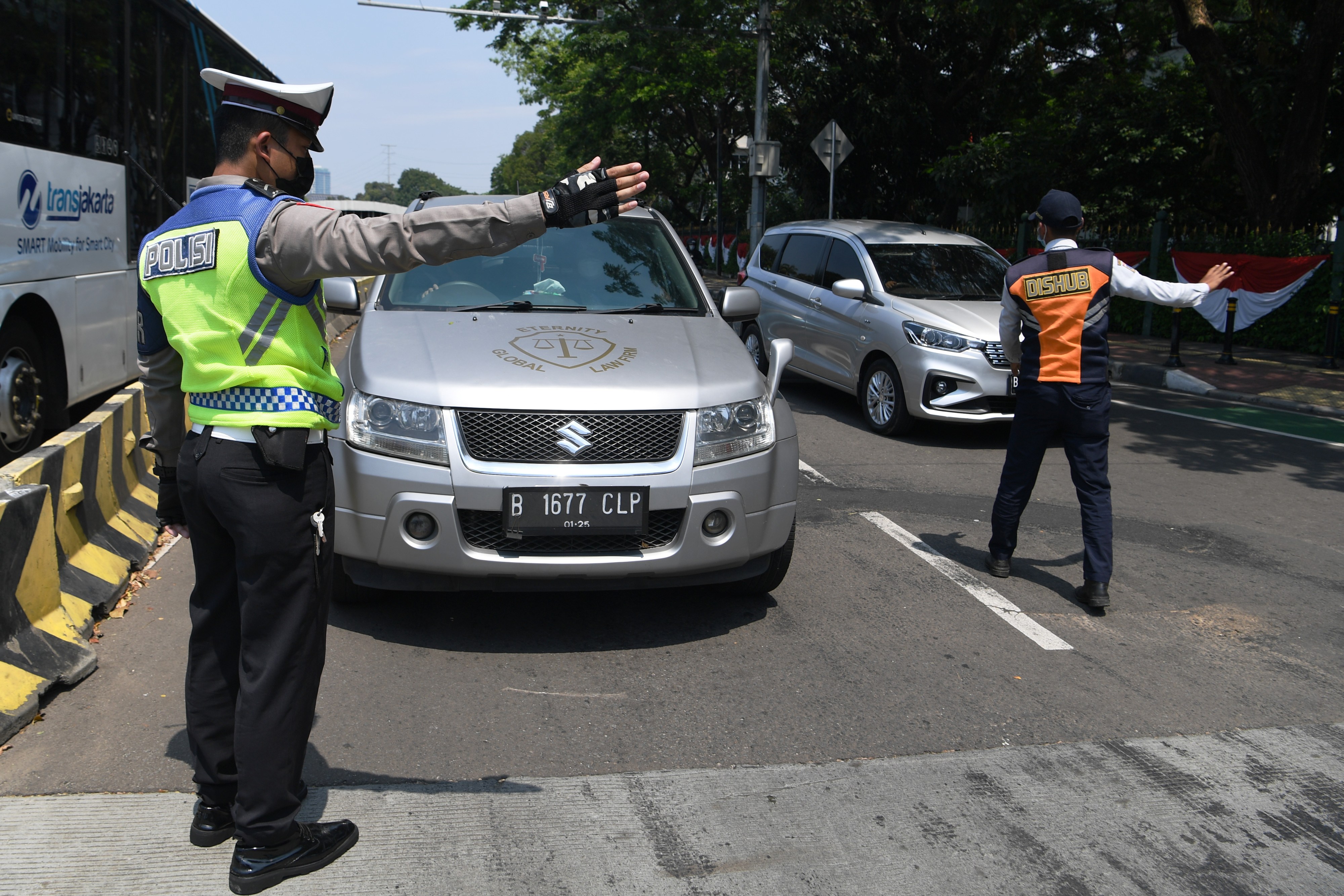 Petugas kepolisian melarang pengendara mobil berplat nomor ganjil memasuki Jalan Sudirman di Bundaran Senayan, Jakarta, Kamis (12/8).
