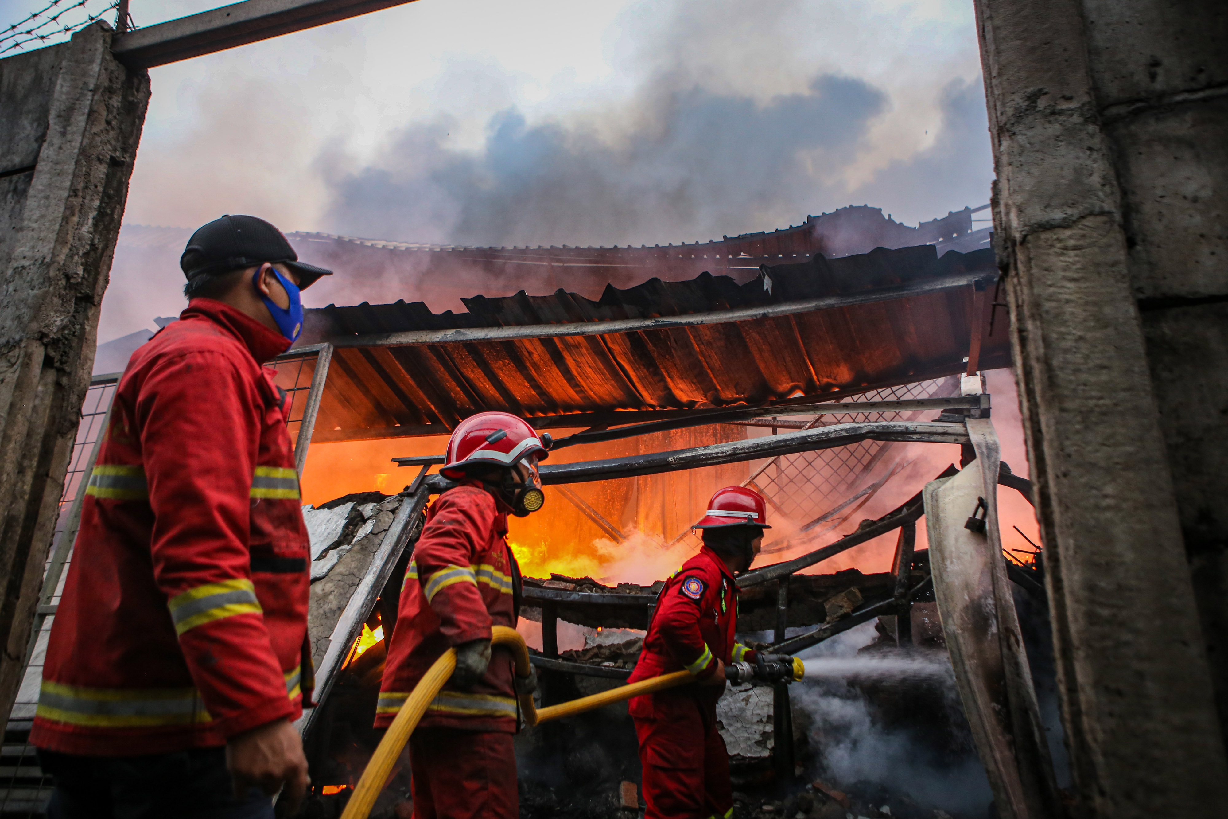 Ilustrasi petugas berusaha memadamkan gedung yang terbakar.