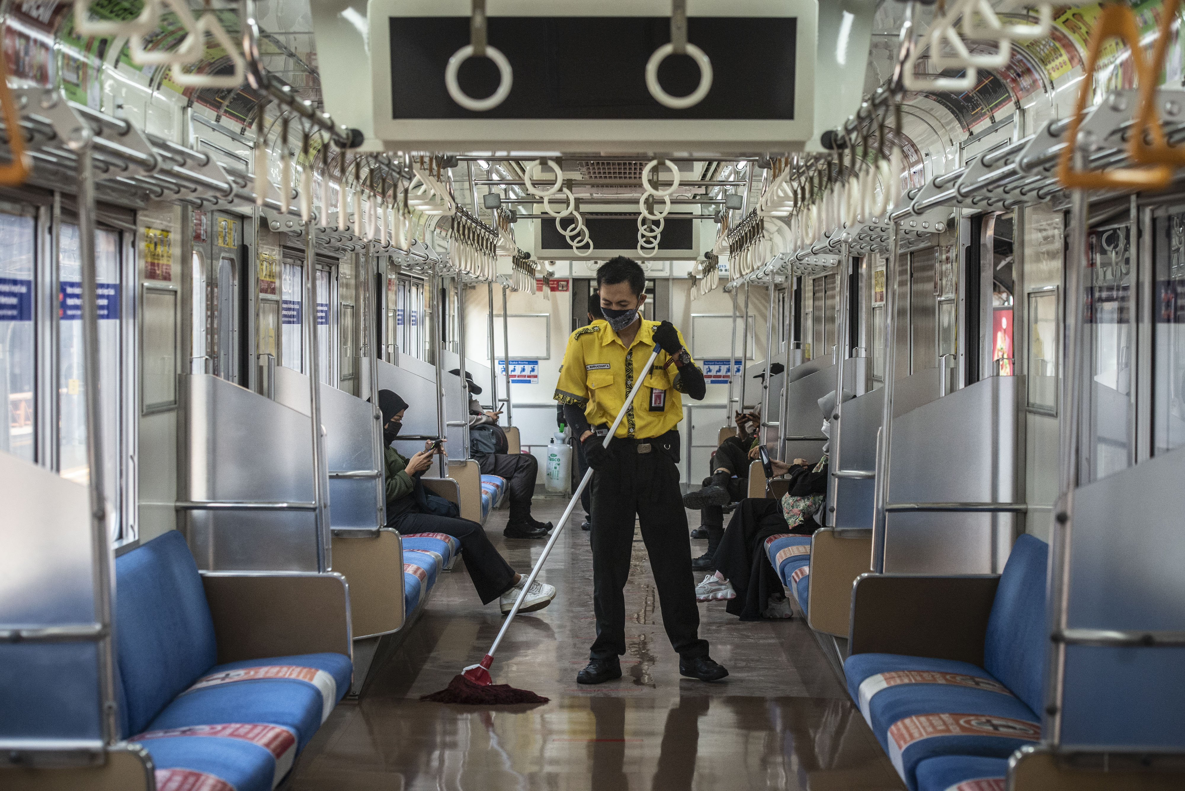 Petugas kebersihan mengepel lantai rangkaian gerbong KRL di Stasiun Jakarta Kota.