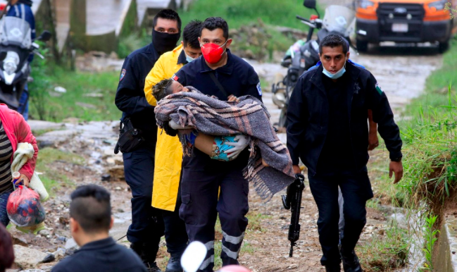 Seorang paramedis keamanan publik membawa seorang anak setelah tanah longsor usai Badai Grace melanda.