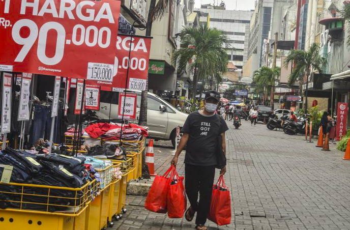 Warga berjalan membawa belanjaannya di kawasan Pasar Baru, Jakarta.