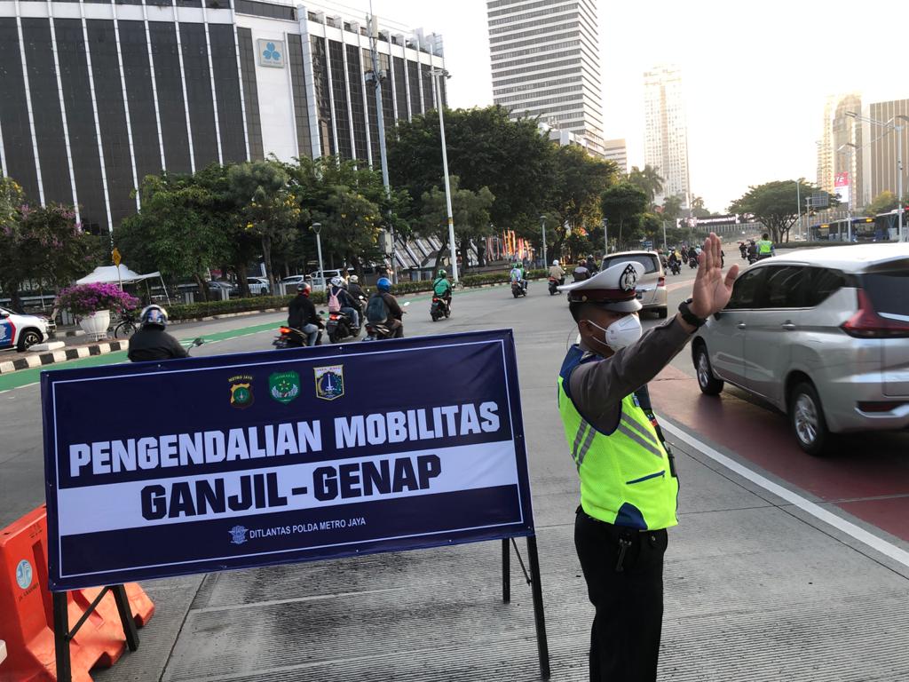 Polisi menyekat di ruas jalan yang menerapkan kebijakan ganjil-genap selama PPKM di Jakarta, Kamis (12/8)