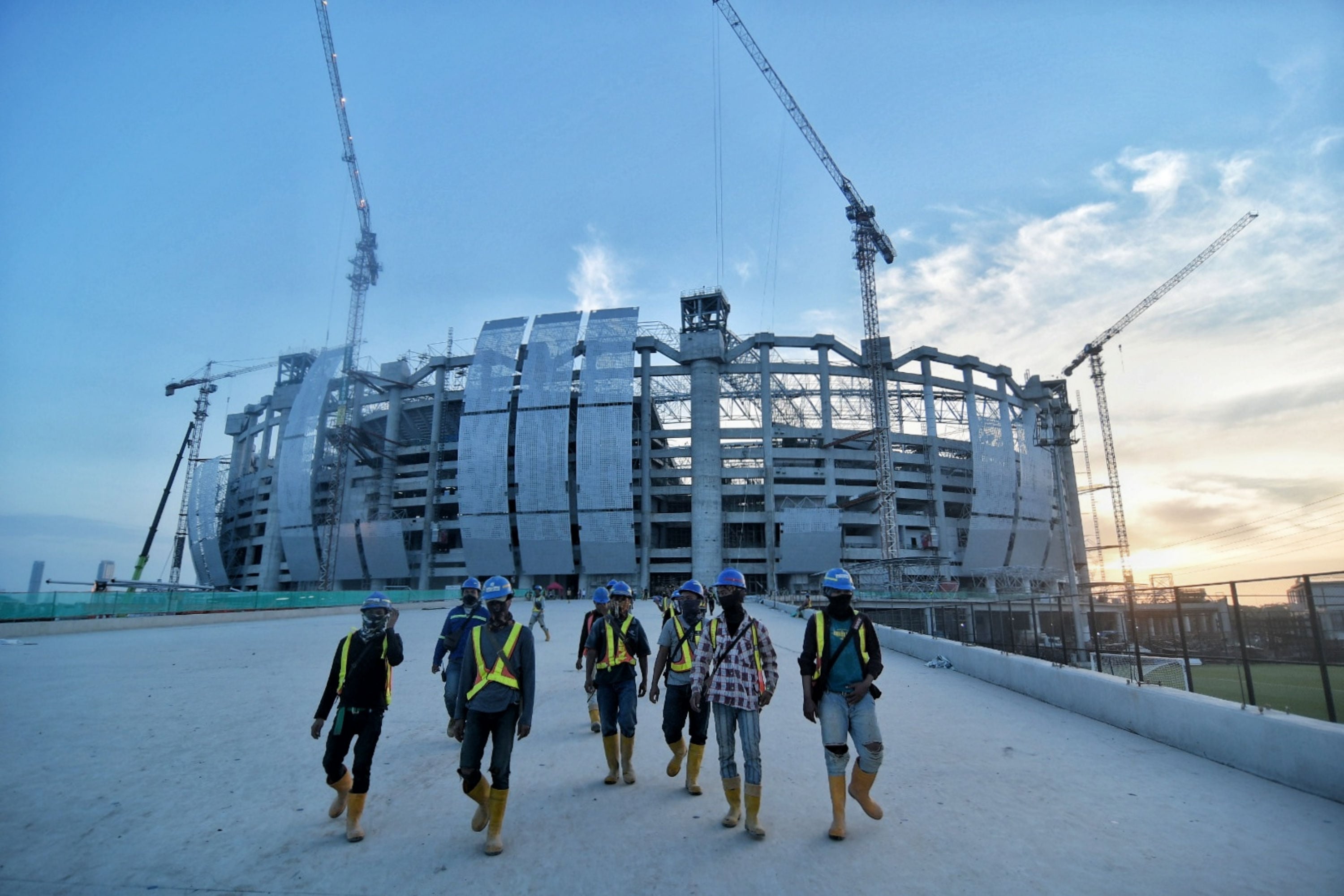Pekerja berjalan keluar dari Jakarta International Stadium usai melakukan pembangunan di Papanggo, Jakarta Utara.