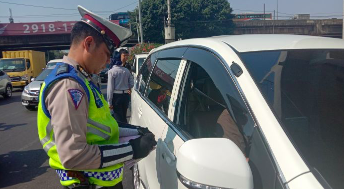 Polisi menilang pengendara yang melanggar ganjil genap di simpang Jalan Panglima Polim Raya, Jakarta Selatan, Selasa (10/9). 