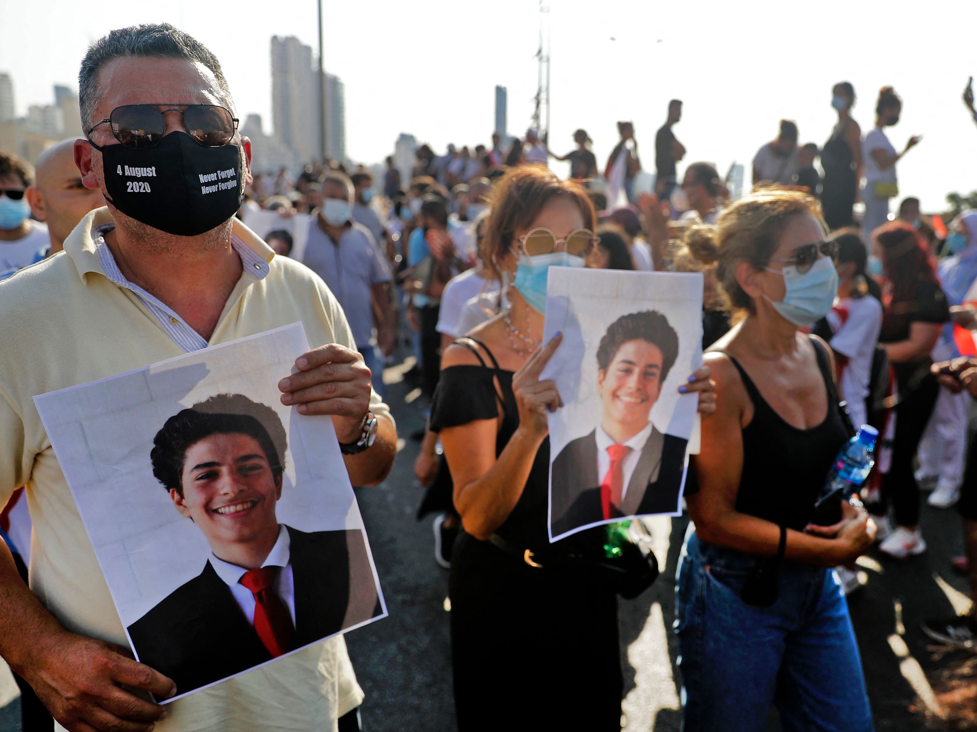 Demonstran mengangkat poster yang menunjukkan wajah para korban ledakan pelabuhan Beirut pada 2020 di luar pelabuhan ibu kota Libanon.