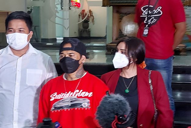 Musisi I Gede Ari Astina alias Jerinx (tengah) didampingi istrinya, Nora Alexandra (kanan) tiba di Polda Metro Jaya, Jakarta, Jumat (13/8). 