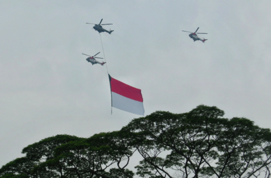 Sejumlah helikopter TNI Angkatan Udara mengibarkan bendera Merah Putih Raksasa mengelilingi Jakarta, Jumat (13/8/2021).