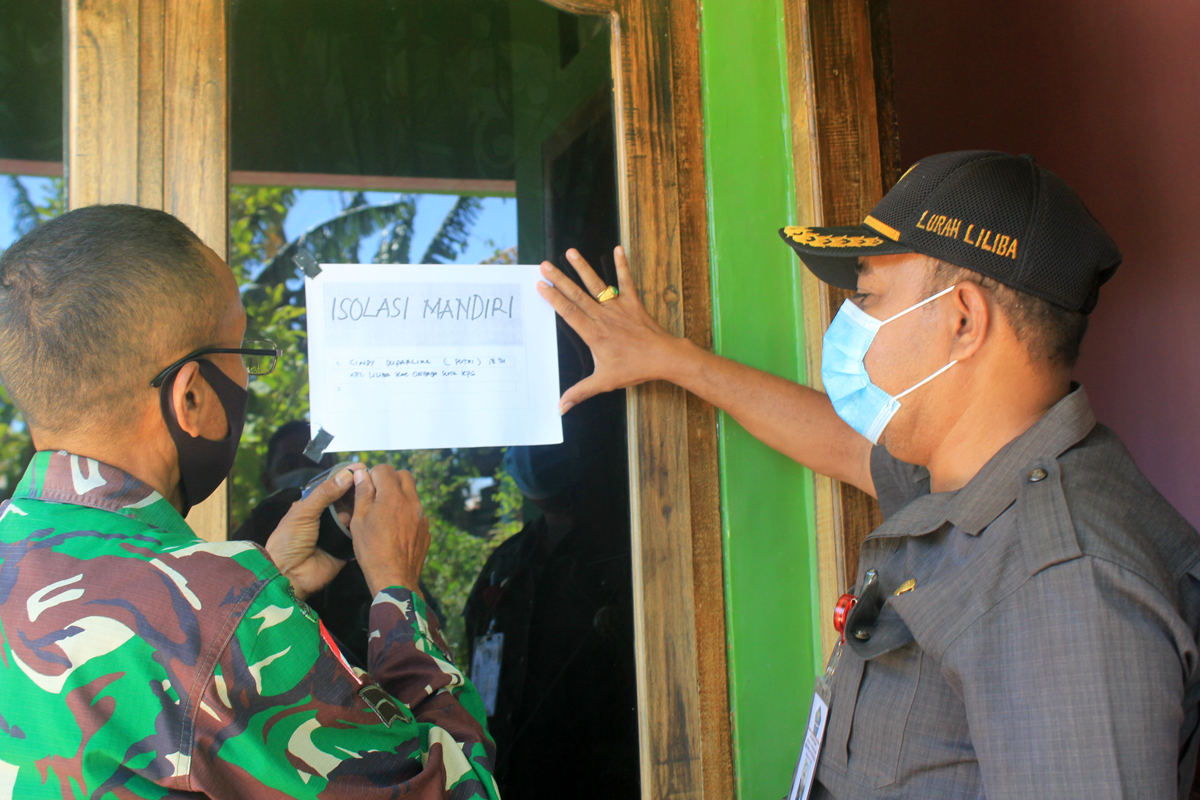 Lurah Liliba, Kota Kupang, NTT, Viktor Makoni (kanan) menempelkan keras bertuliskan Isolasi Mandiri di rumah warga, Rabu (4/8). 