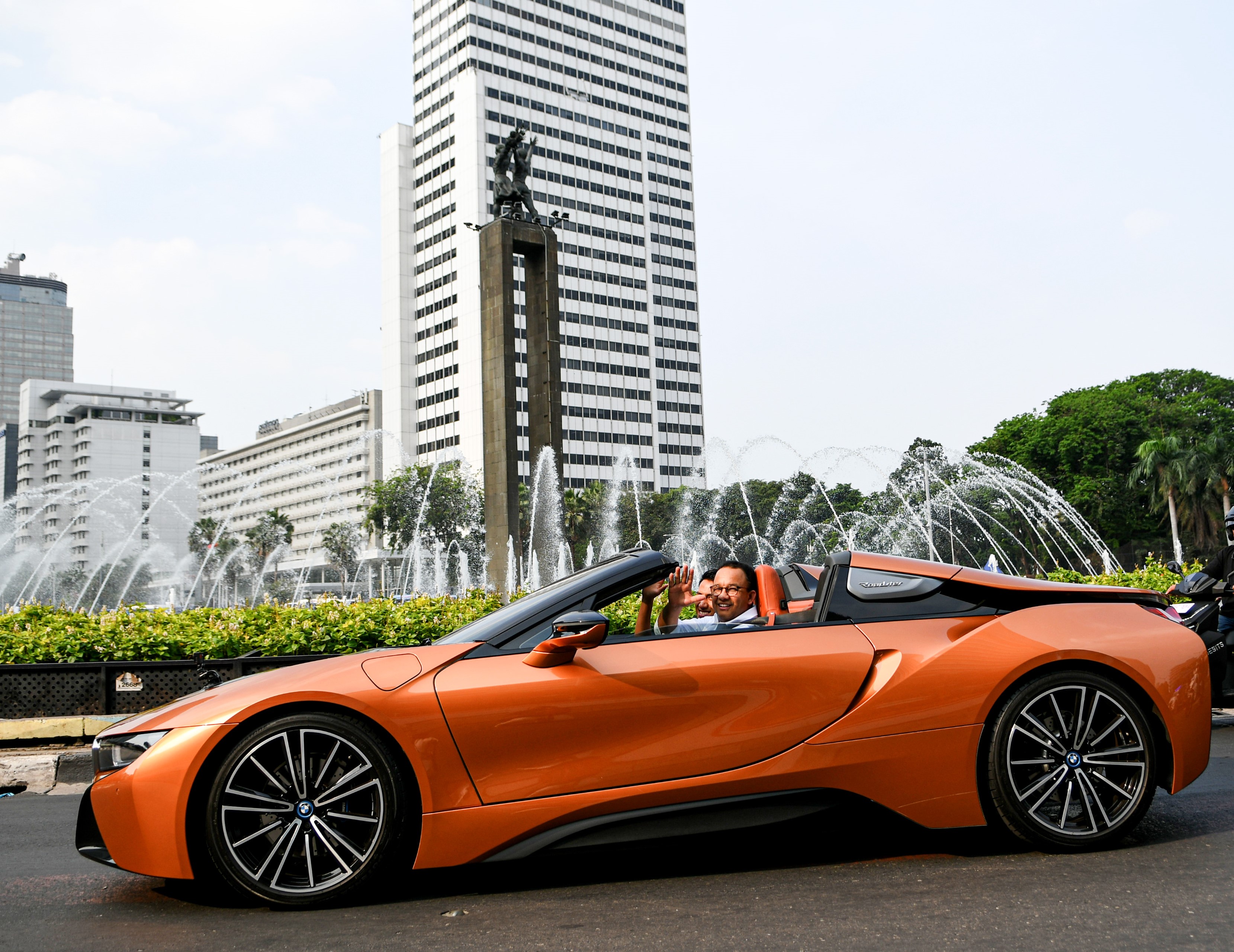 Gubernur DKI Anies Baswedan didampingi pembalap Sean Gelael saat mengendarai mobil listrik.