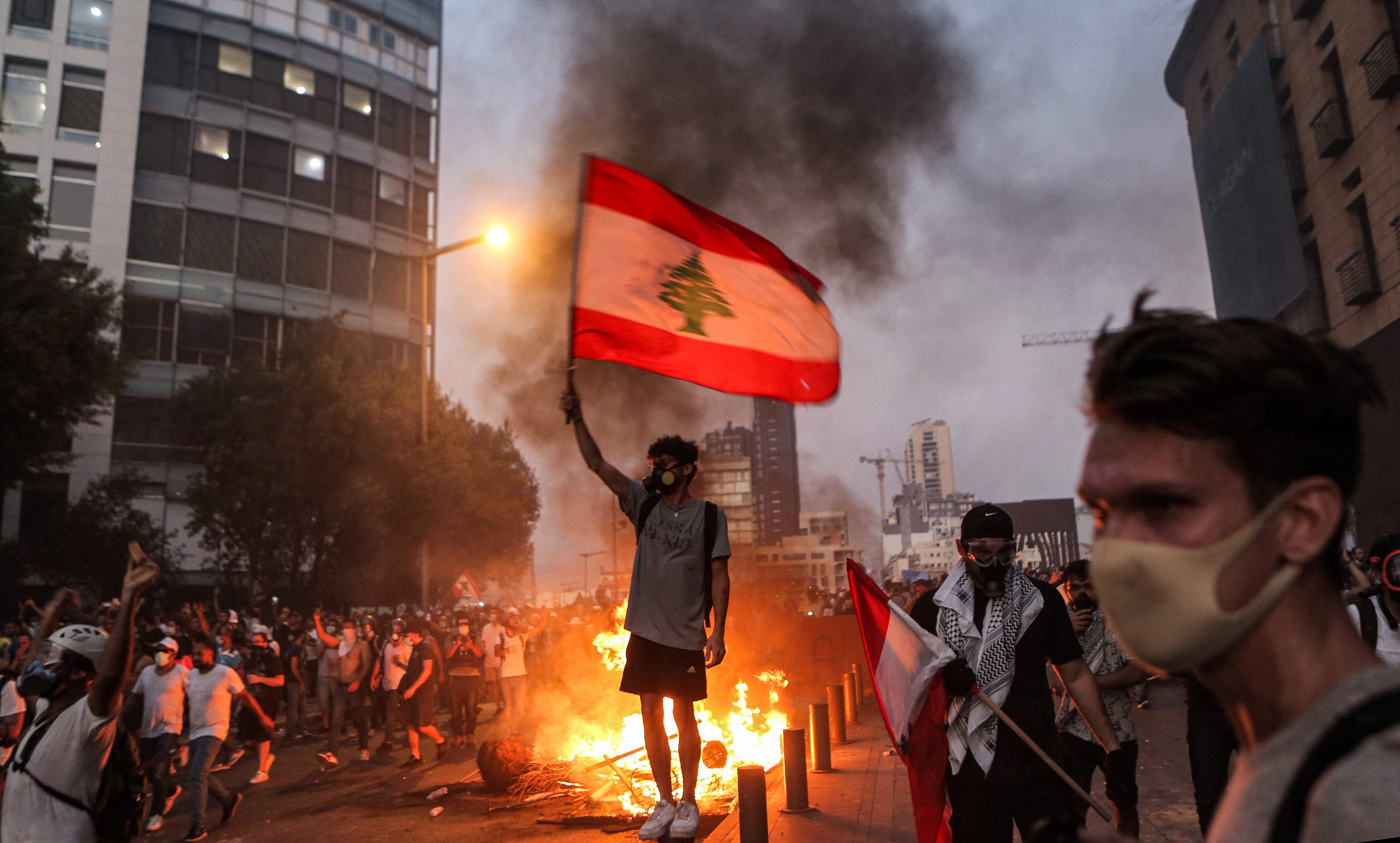 Seorang demonstran mengibarkan bendera Libanon dalam aksi unjuk rasa di Beirut.