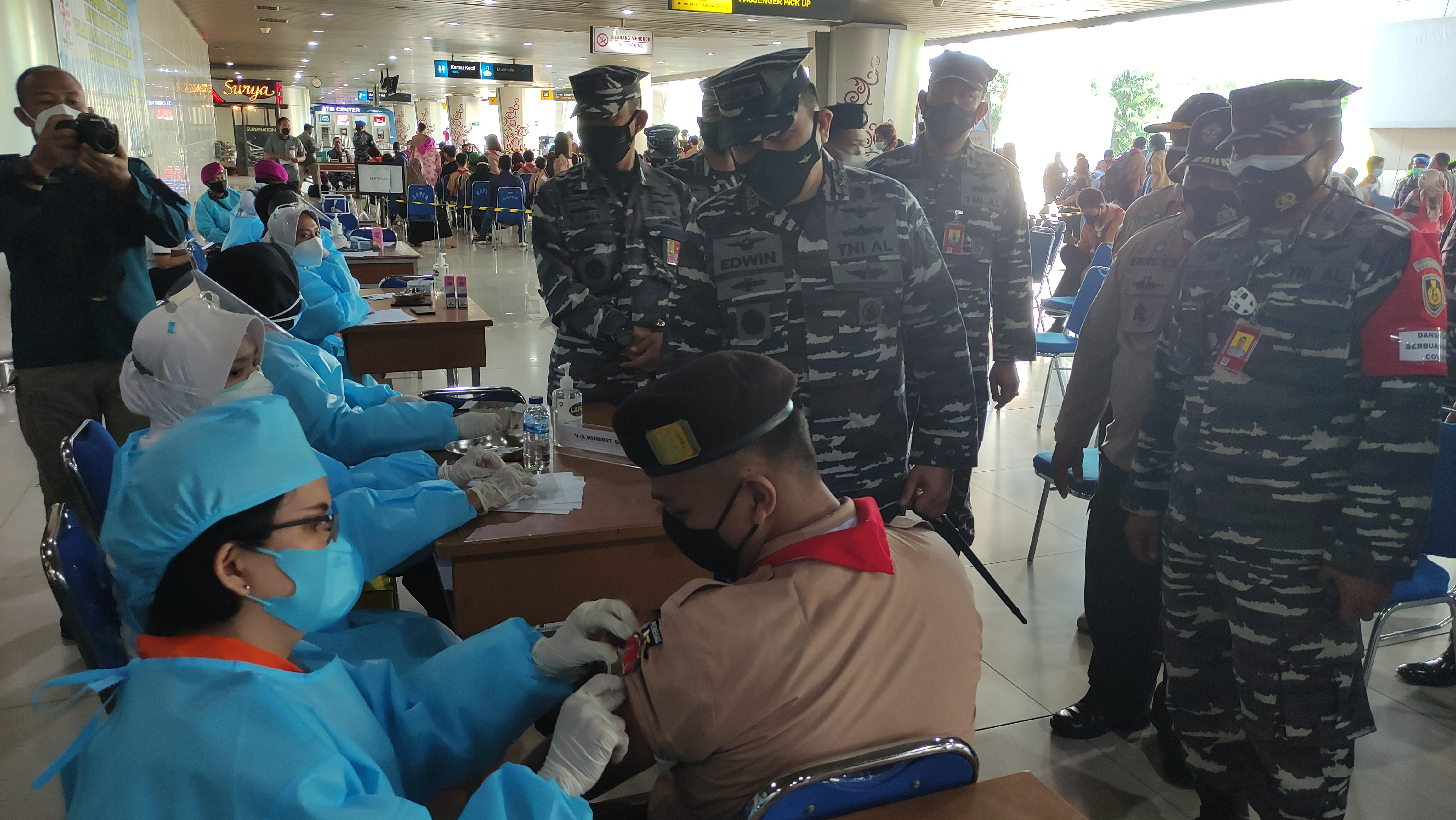 Pelajar berseragam pramuka menjalani vaksinasi dosis pertama yang diadakan Pusat Penerbangan Angkatan Laut  Terminal 2 Bandara Juanda. 