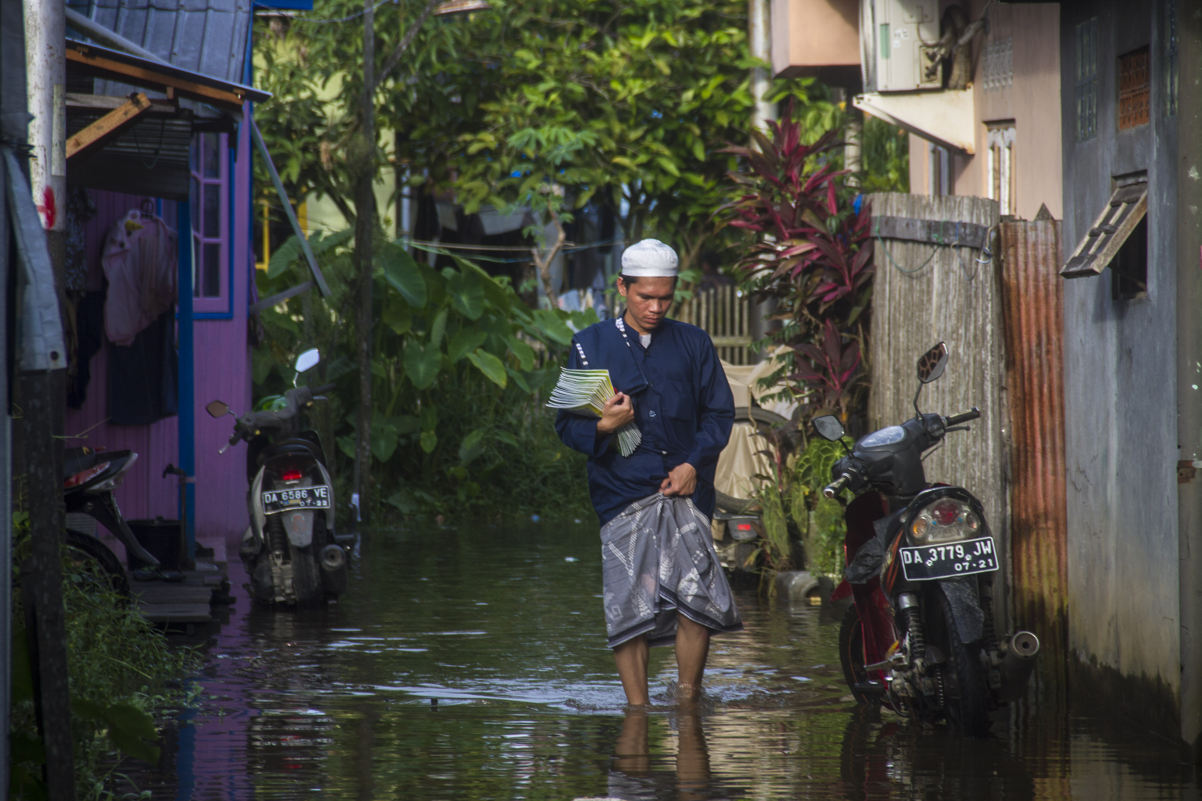 Seorang warga melintasi banjir akibat luapan Sungai Martapura di Kelayan A, Banjarmasin, Kalimantan Selatan, Senin (5/4/2021).