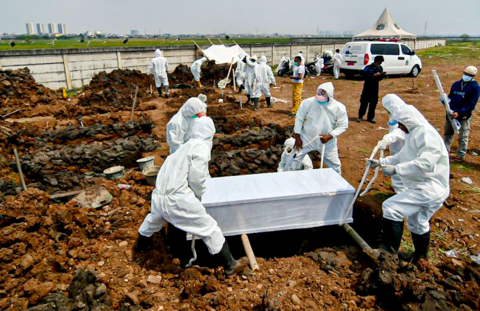 Petugas dengan APD lengkap memakamkan jenazah pasien covid-19 di TPU Rorotan, Jakarta.