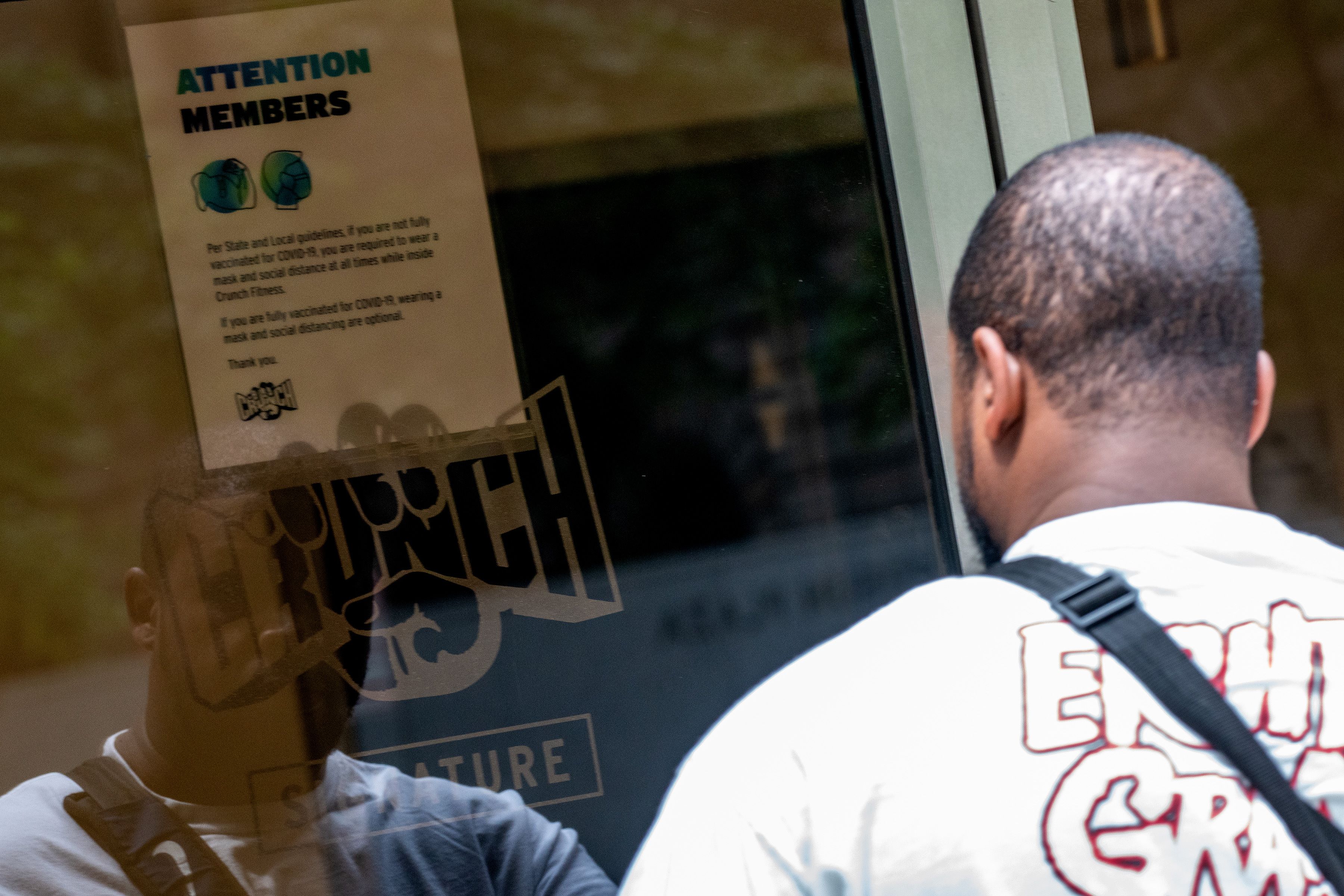 Seorang warga membaca aturan protokol kesehatan saat akan memasuki sebuah pusat kebugaran di New York, AS.