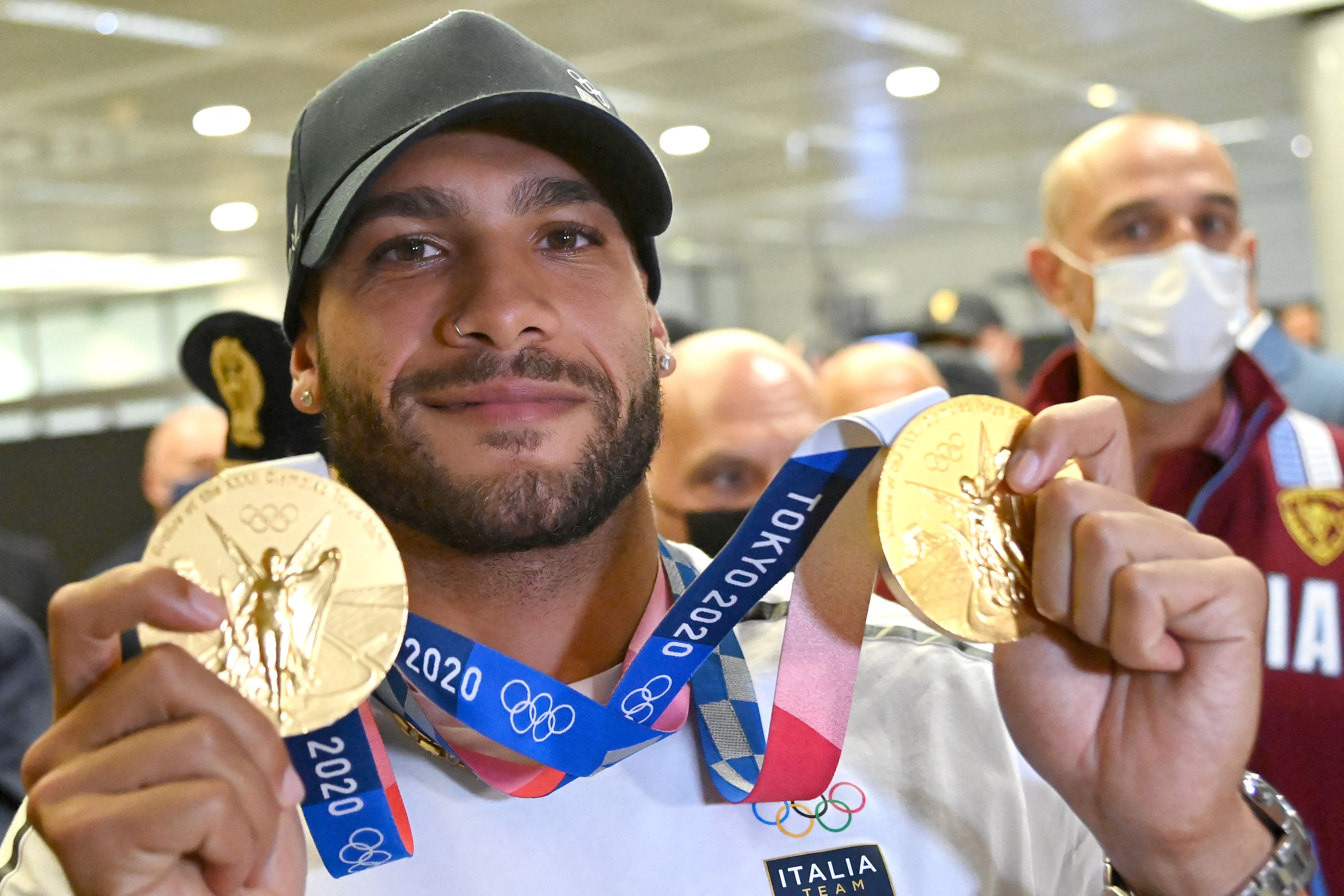 Sprinter Italia Lamont Marcell Jacobs memamerkan dua medali emas yang dimenangkannya di Olimpiade Tokyo 2020 saat tiba di Roma.