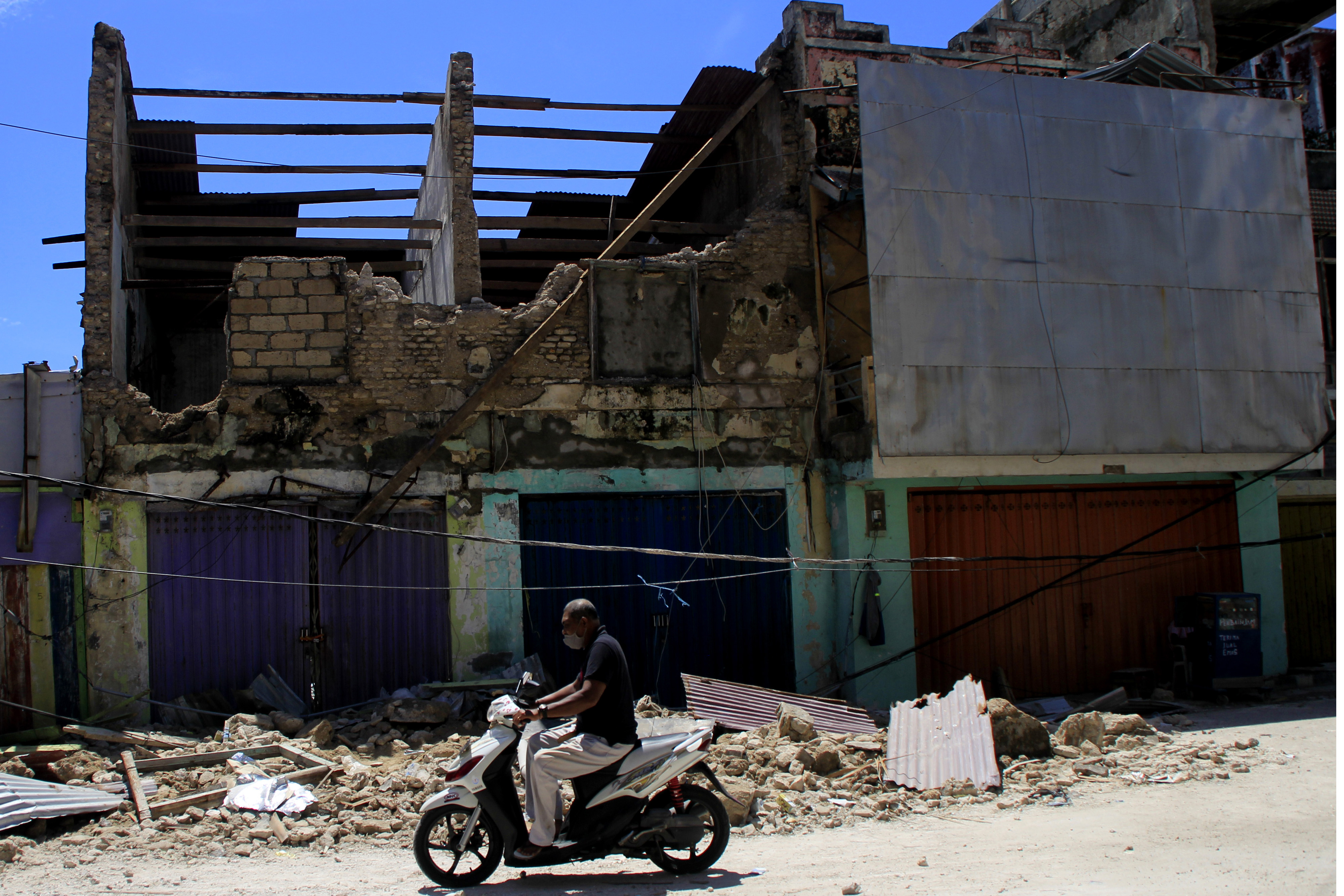 Seorang pengendara bermotor melintas di depan salah satu gedung yang ambruk akibat badai Seroja di Kota Kupang, NTT, 8 April 2021.