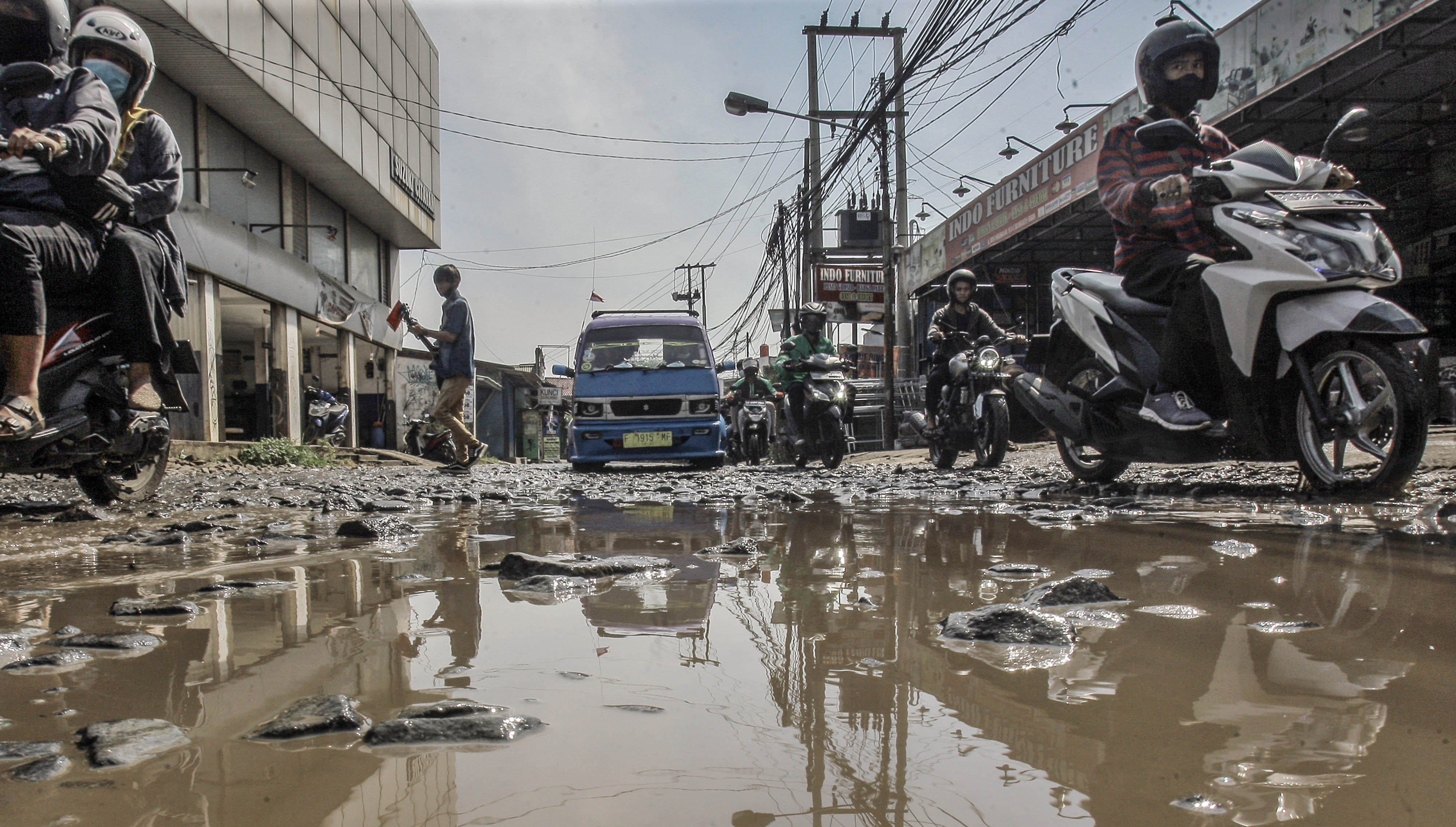 Pengendara melintasi jalan penghubung antara Kabupaten Bogor dan Kota Depok yang rusak di Pabuaran, Kabupaten Bogor, Jawa Barat, Jumat (6/8/