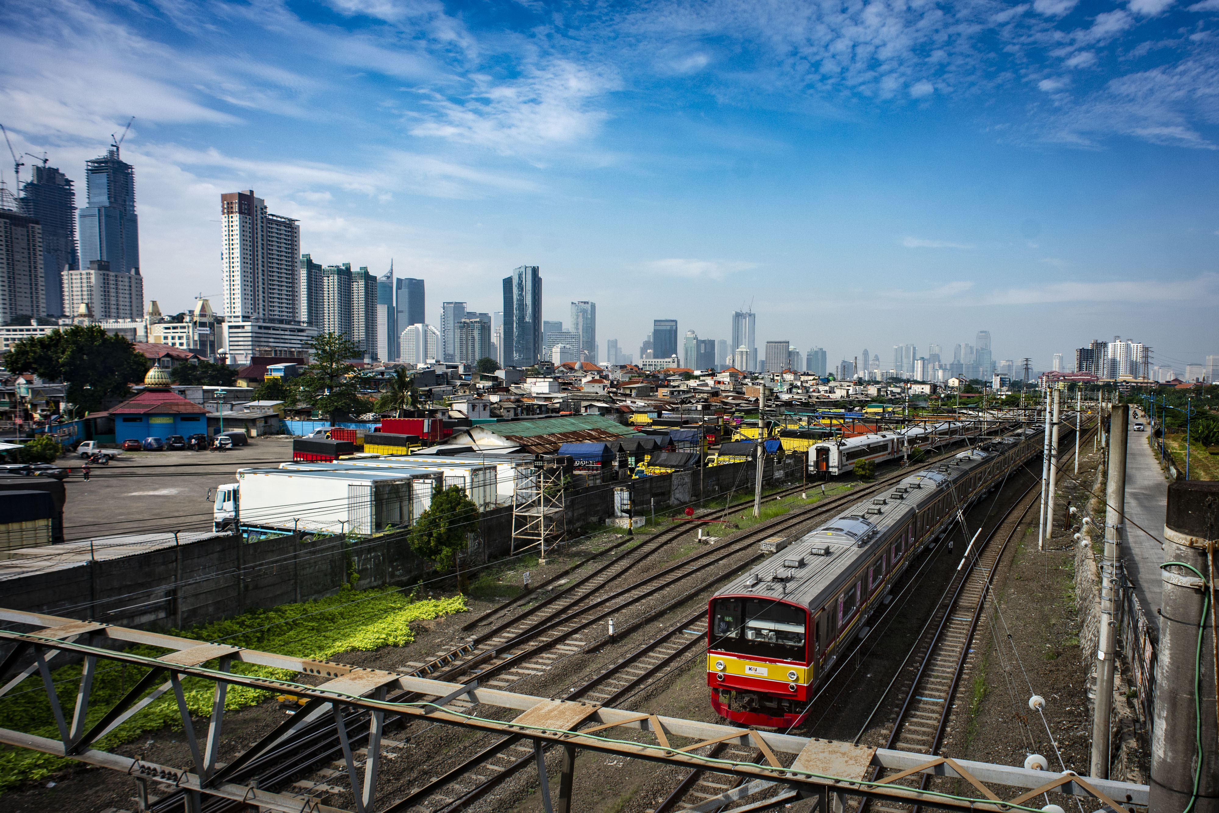 KRL melintas dengan latar belakang permukiman penduduk dan gedung bertingkat di Jakarta.
