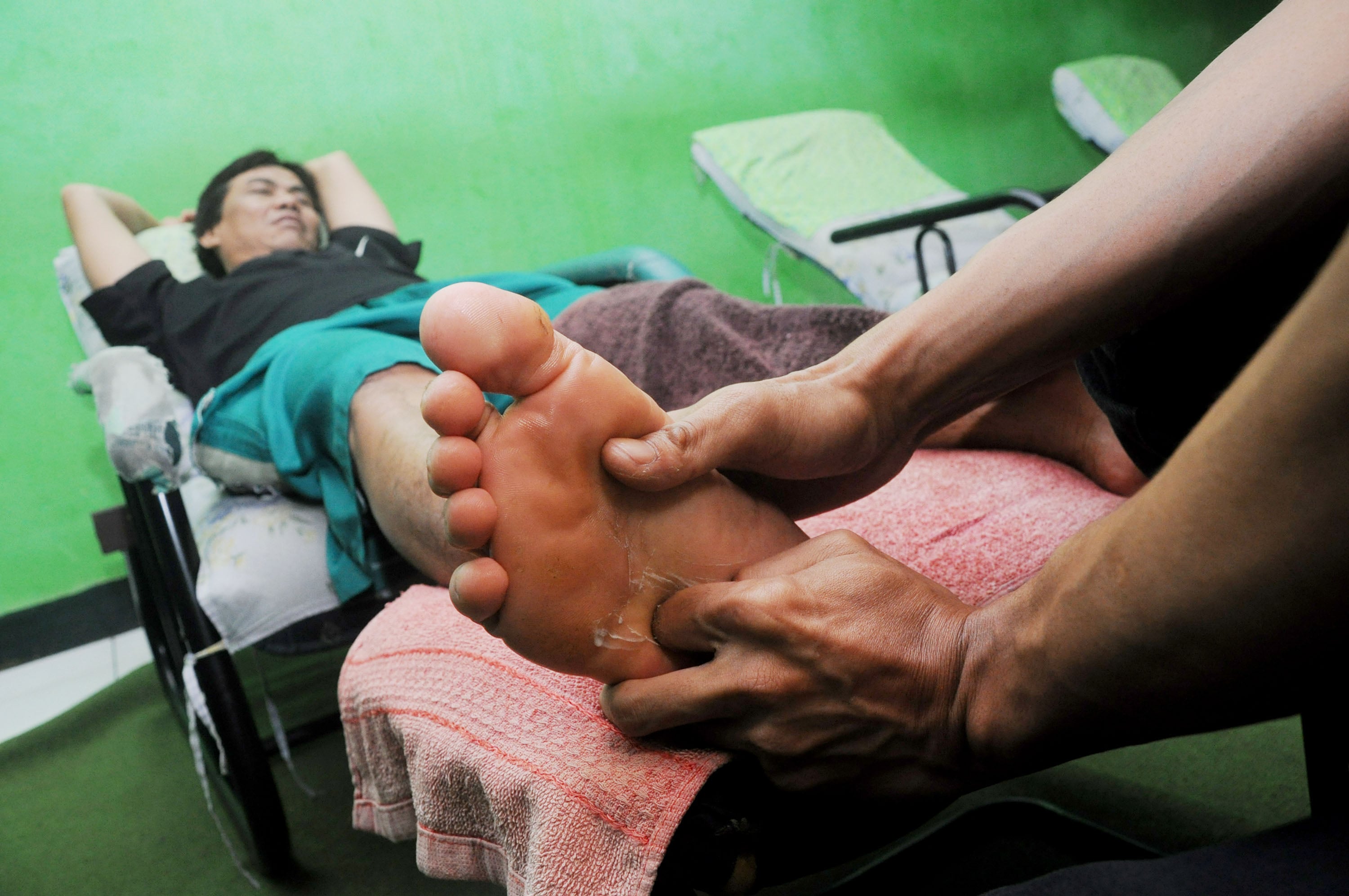 Seorang warga sedang melakukan terapi pijat refleksi untuk kesehatan tubuh.