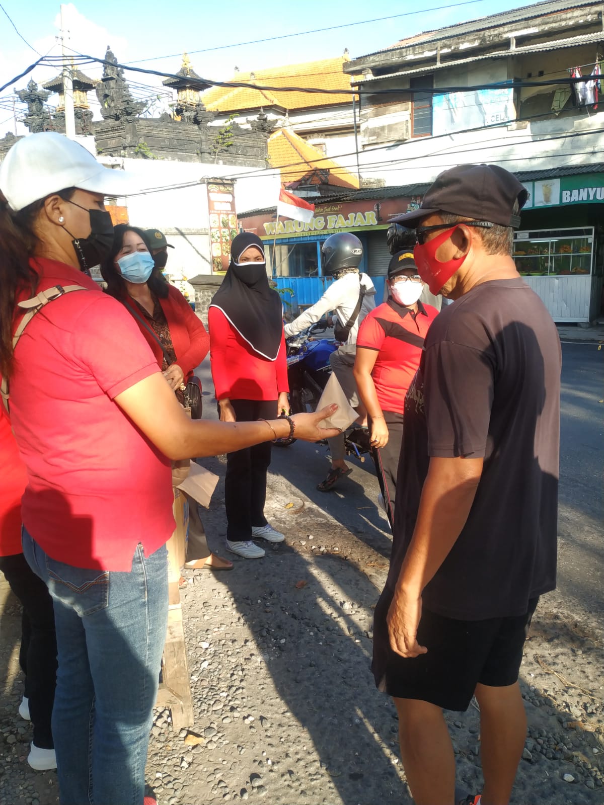 Seorang ibu PKK Desa Pemogan, Denpasar, Bali, menyerahkan nasi bungkus untuk warga
