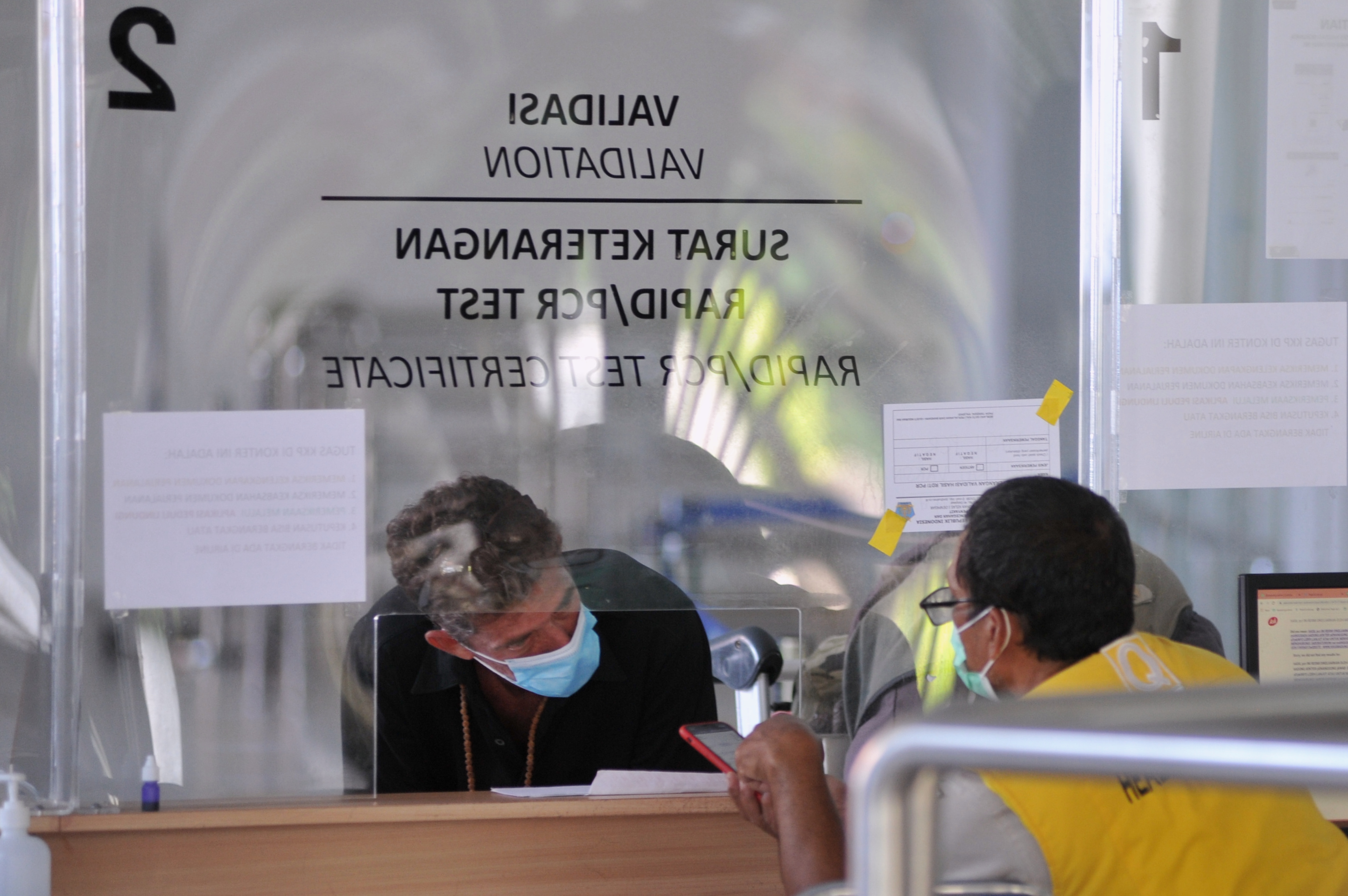 Petugas memeriksa dokumen kesehatan calon penumpang pesawat di Terminal Domestik Bandara Internasional I Gusti Ngurah Rai, Bali.