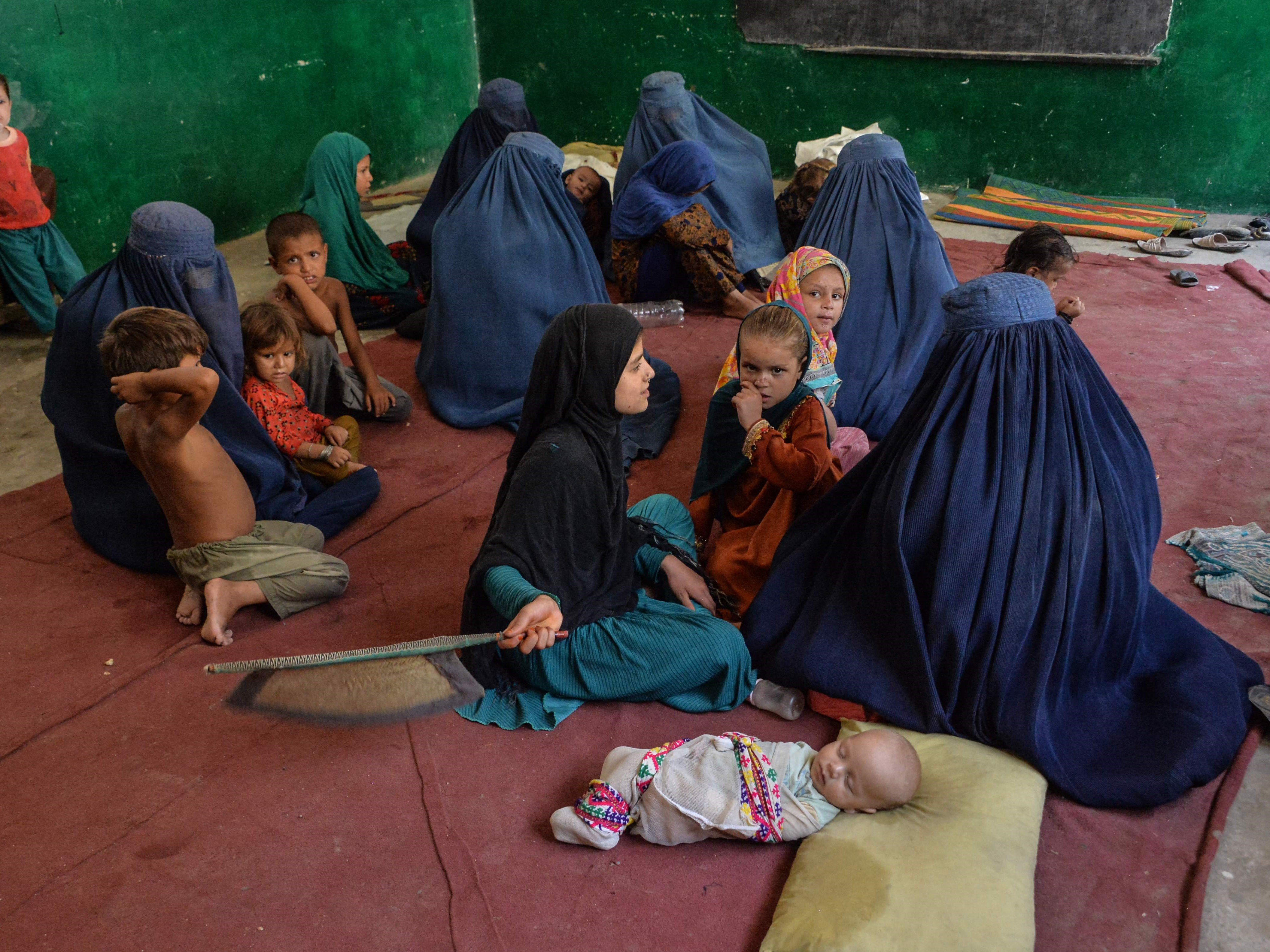 Keluarga pengungsi duduk di dalam sekolah setelah mereka meninggalkan rumah setelah pertempuran antara pasukan Afghanistan dengan Taliban.