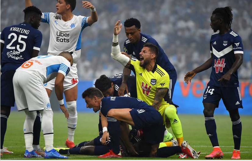 Para pemain mengerumuni striker Bordeaux Samuel Kalu, yang pingsan dalam pertandingan Ligue 1 di kandang Bordeaux, Minggu (15/8).