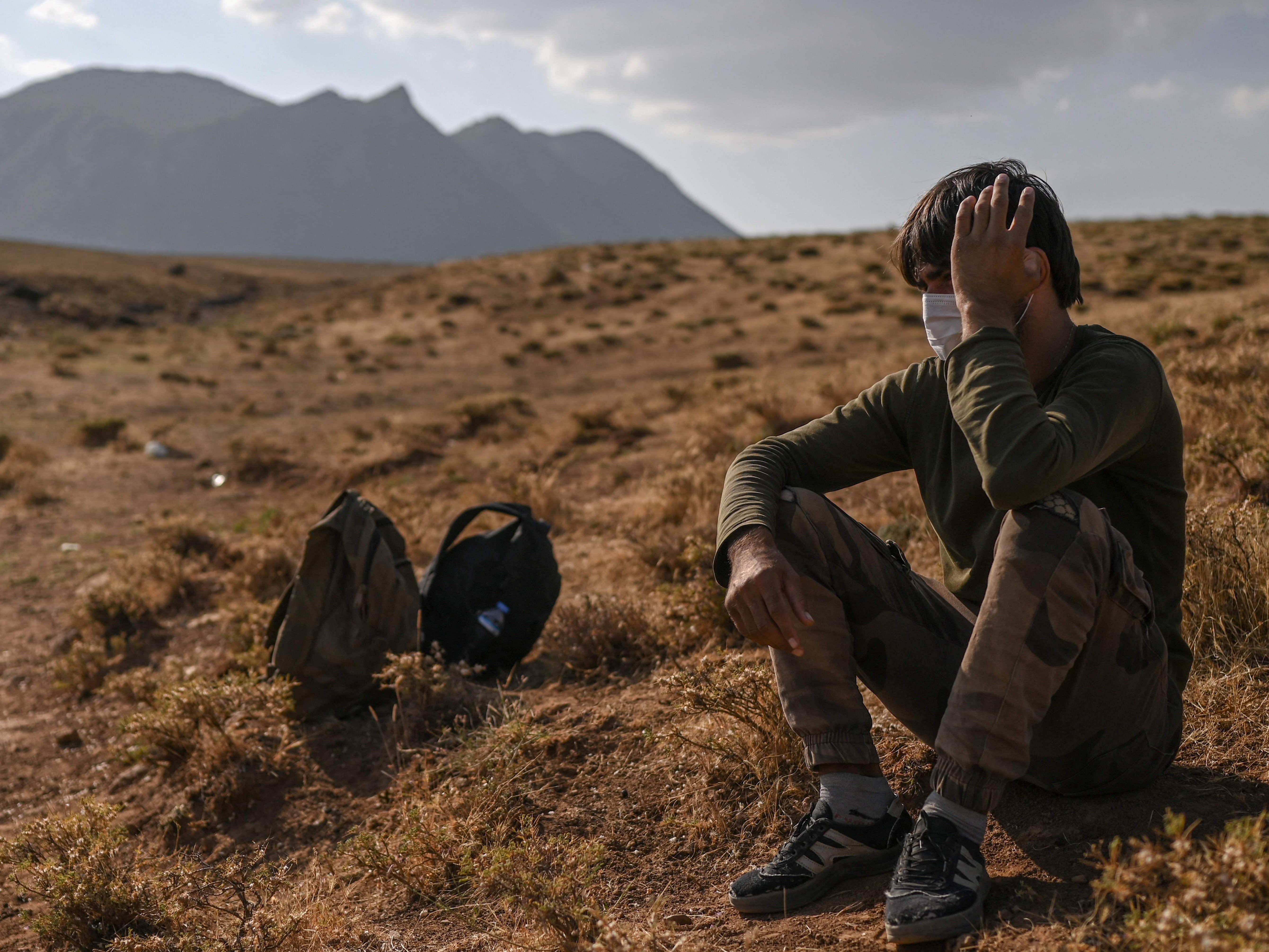 Seorang migran Afghanistan beristirahat sambil menunggu transportasi oleh penyelundup setelah melintasi perbatasan Iran-Turki.