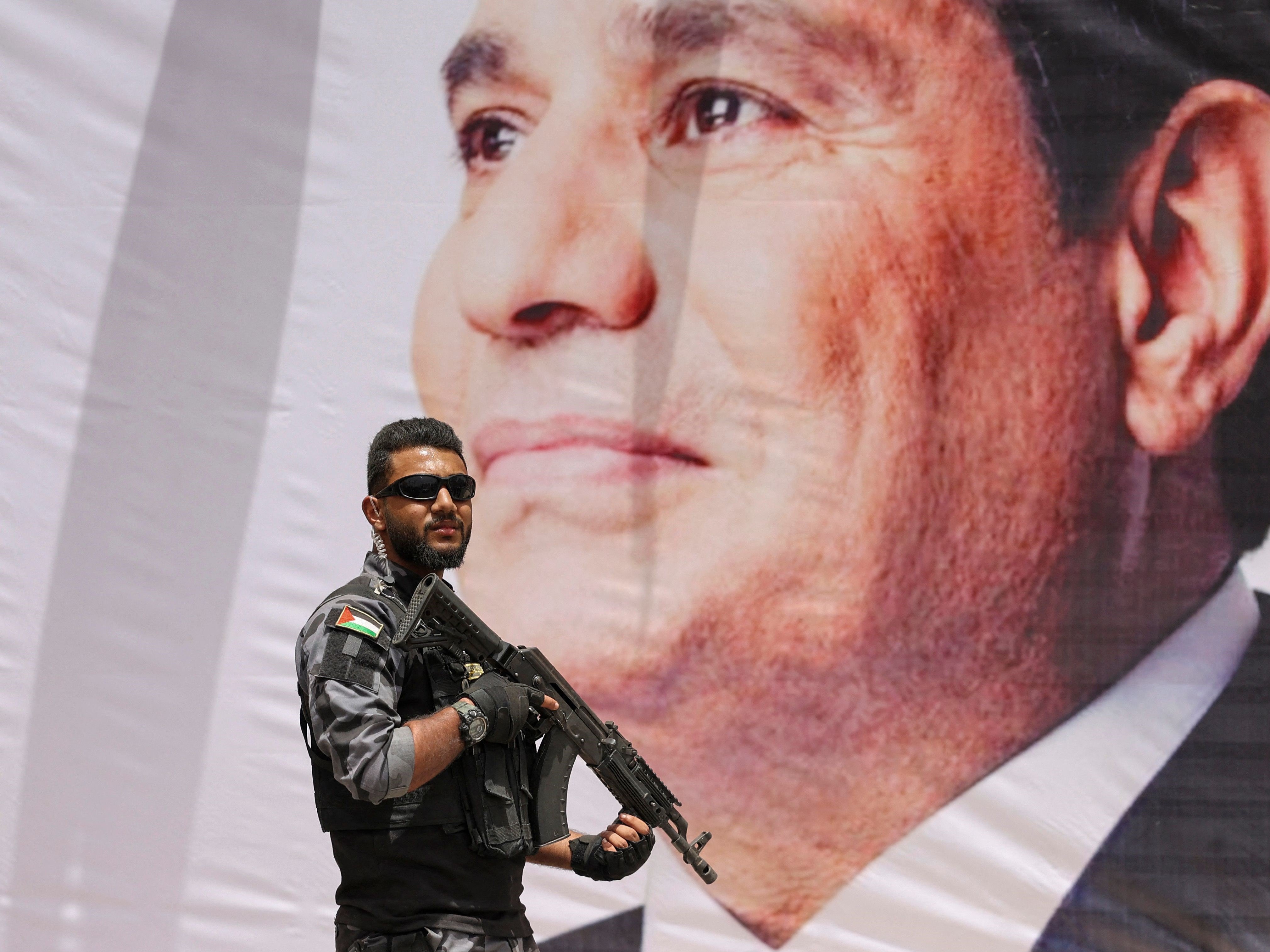 Anggota keamanan Hamas berjaga di depan spanduk bergambar Presiden Abdel Fattah al-Sisi.