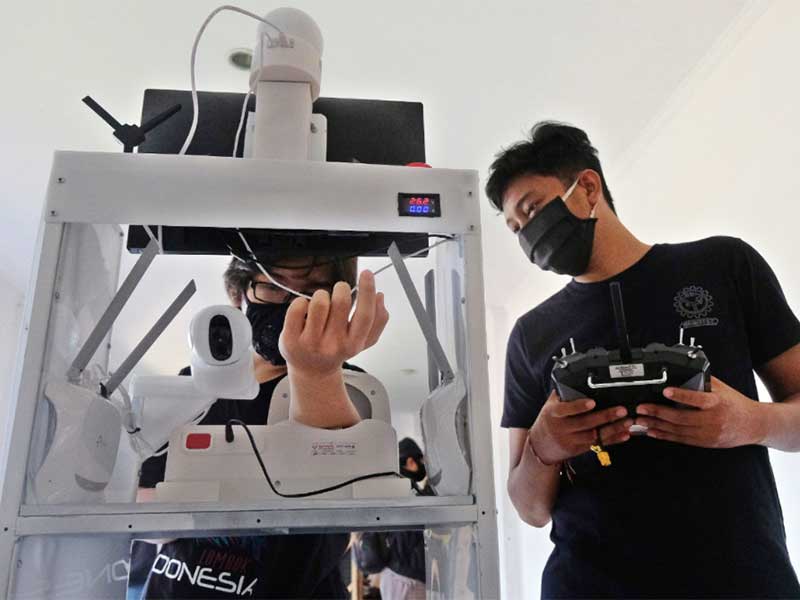 Mahasiswa memeriksa tekanan darah dengan menggunakan robot rakitan saat melakukan uji coba di ruang UKM Robotec Universitas Udayana Denpasar