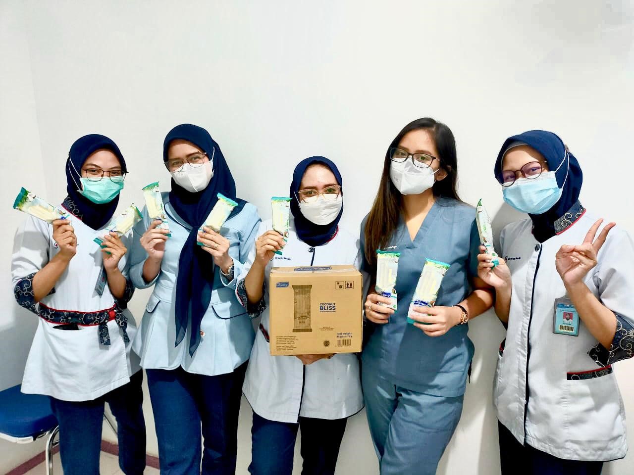 Tenaga kesehatan menikmati es krim yang diberikan perusahaan.