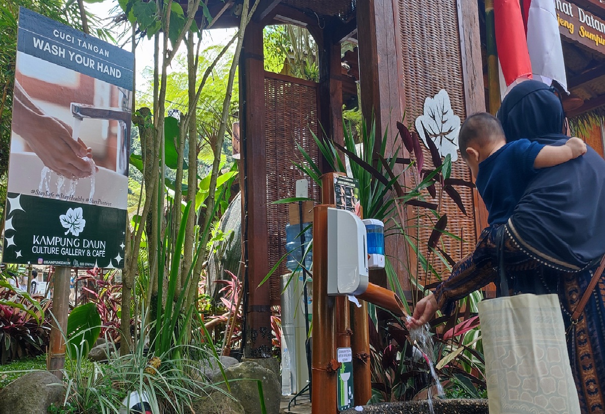 Pengunjung cuci tangan sebelum masuk ke area Kampung Daun Parongpong, Lembang, Jawa Barat, Sabtu (14/8). 