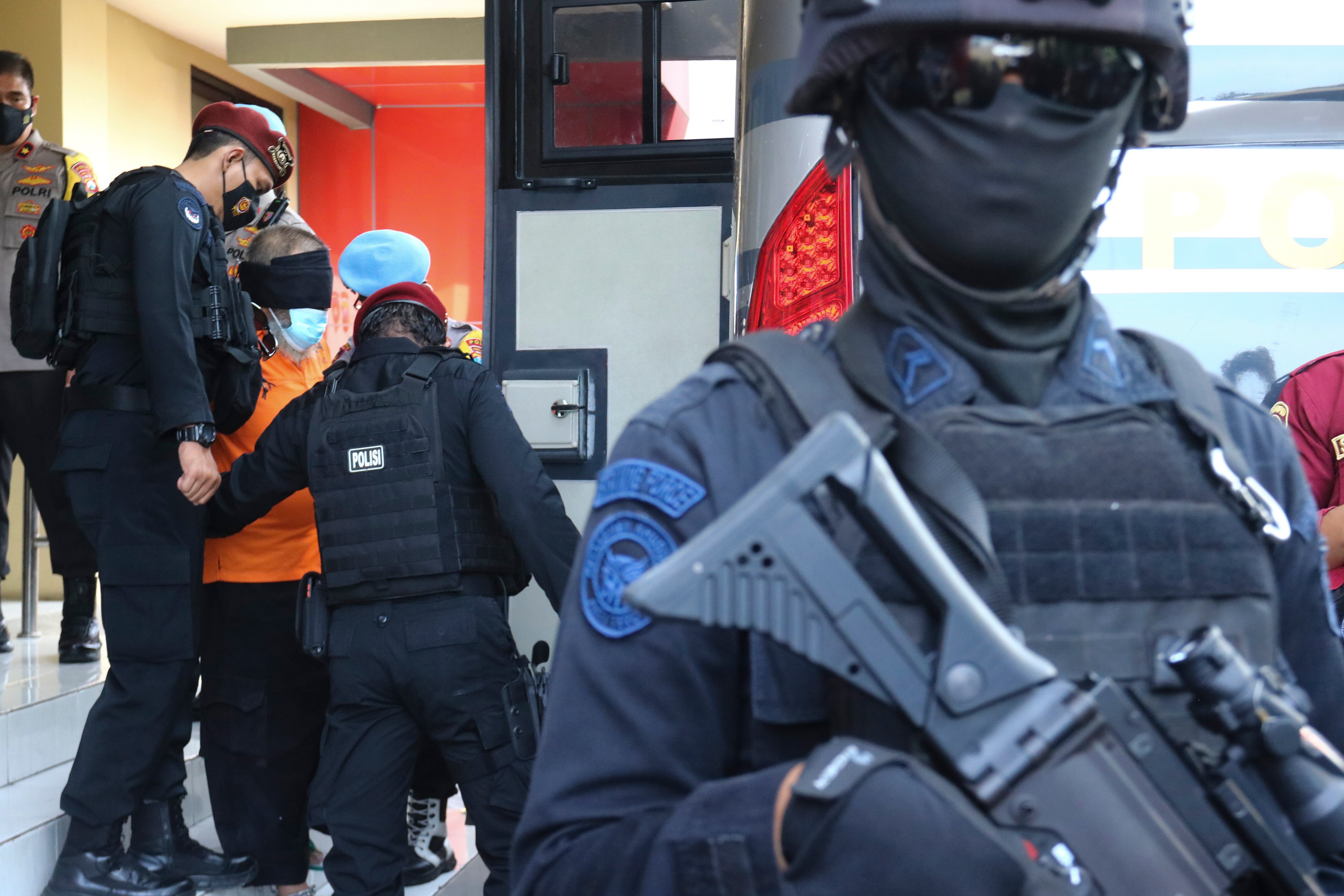 Personel Densus 88 saat membawa terduga teroris ke dalam bus di Polda Jawa Timur.