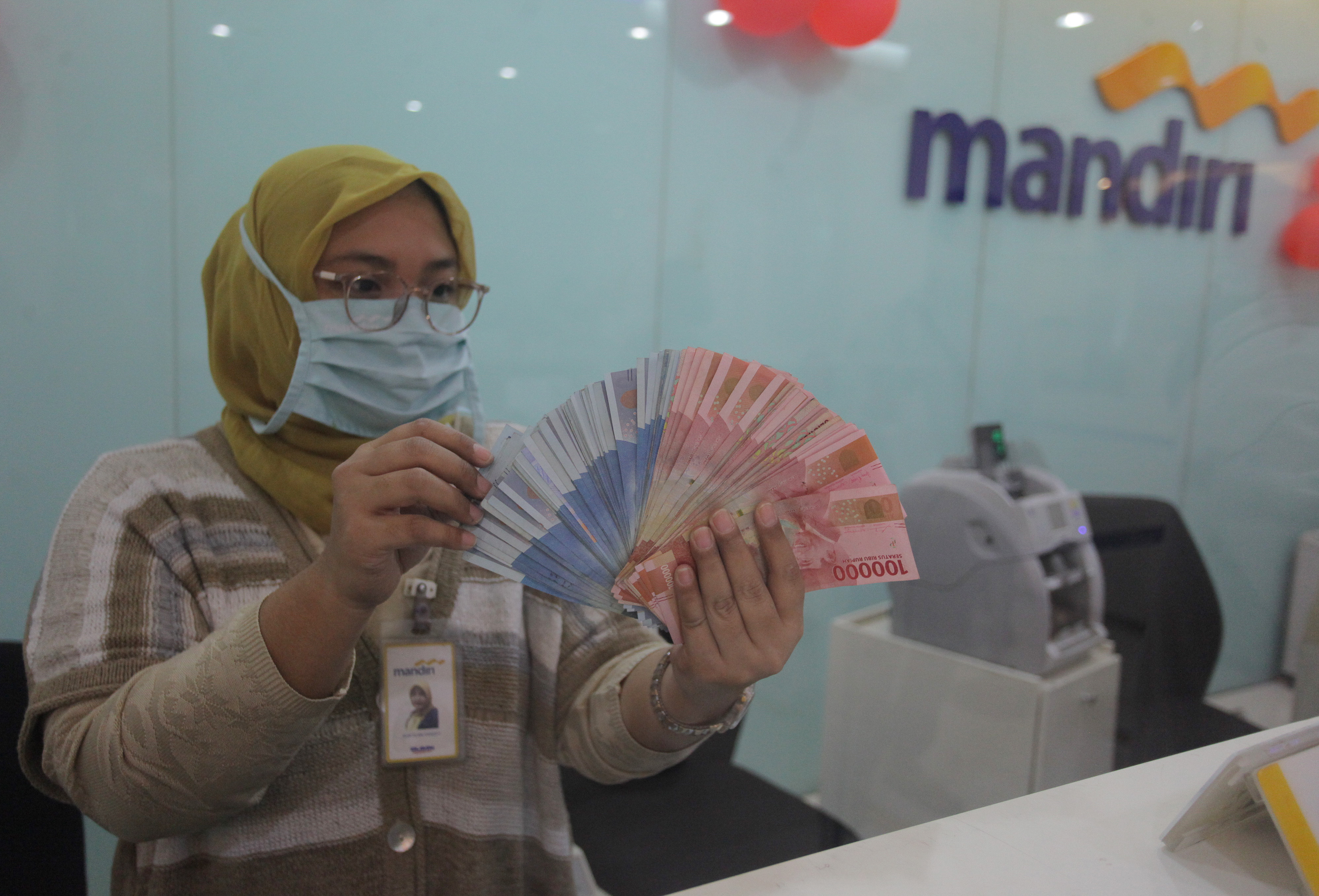 Petugas perbankan menghitung uang rupiah