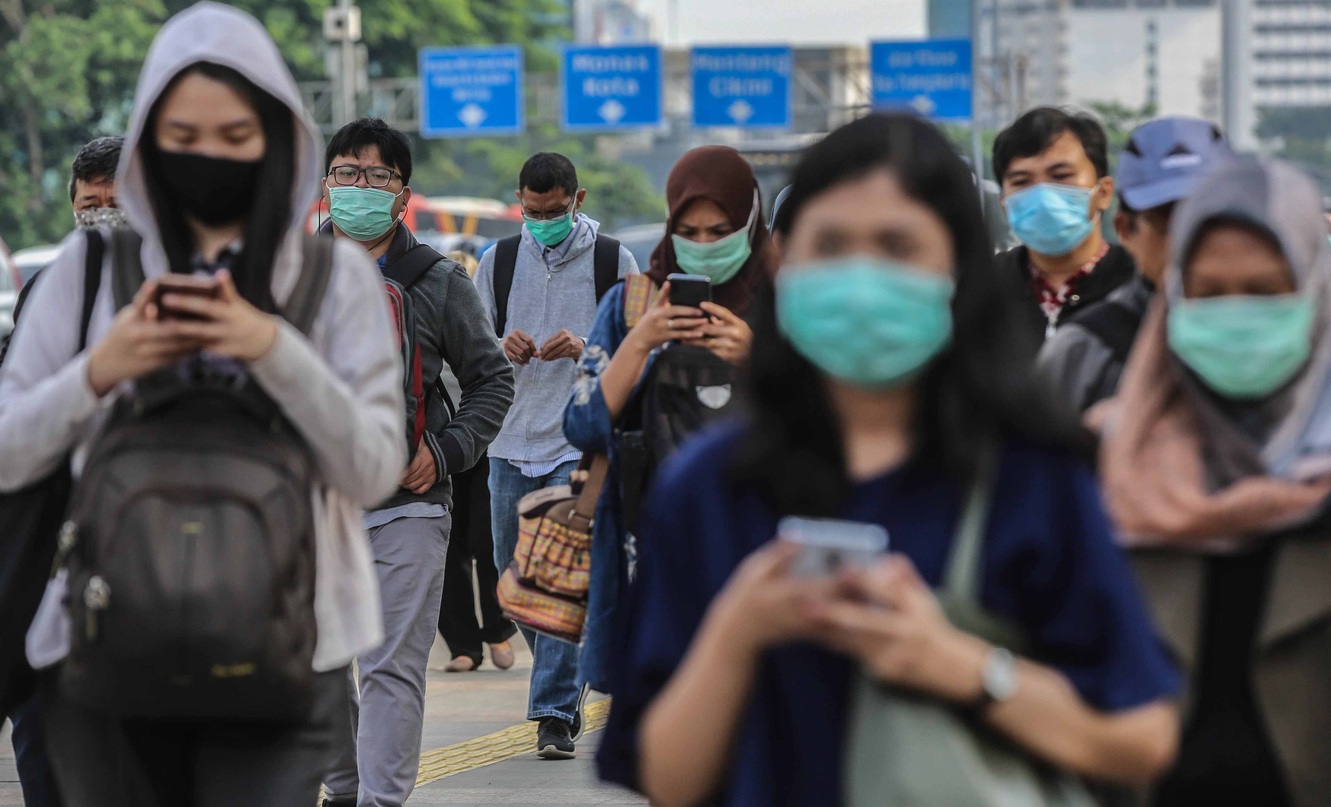  Pekerja menggunakan masker pelindung saat melewati trotoar menuju kantornya di kawasan Sudirman, Jakarta.