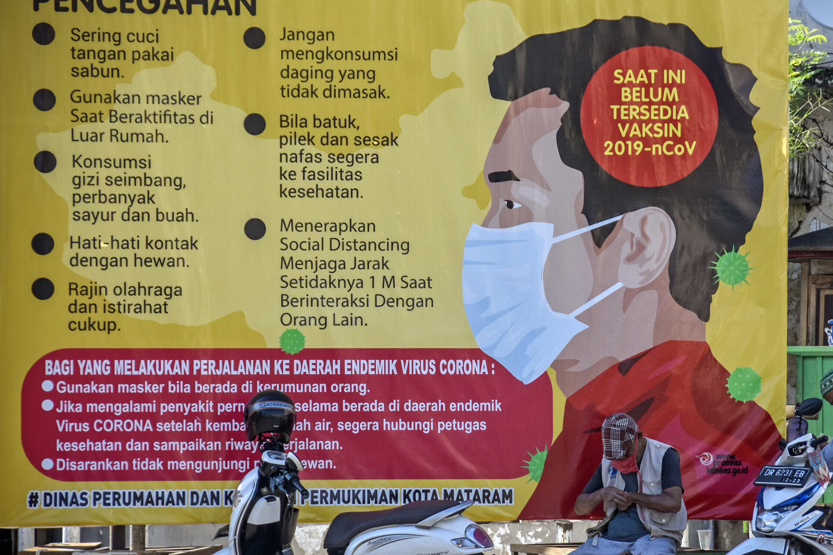 Tukang ojek menunggu penumpang dekat baliho sosialisasi covid-19 yang terpasang di simpang lima Kota Tua Ampenan, Mataram, NTB.