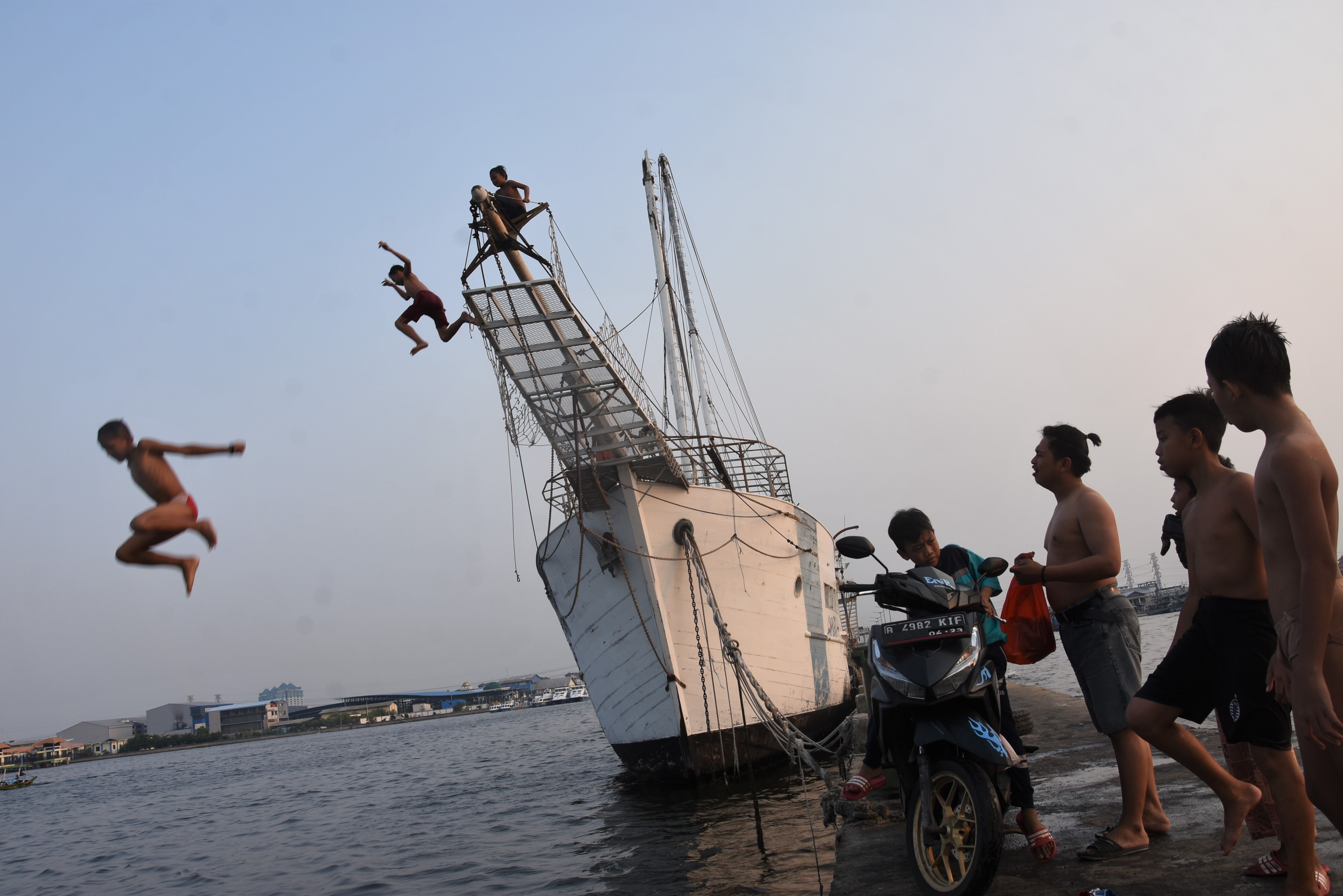 Sejumlah anak melompat dari atas kapal yang bersandar di Pelabuhan Kali Adem, Jakarta, beberapa waktu lalu.