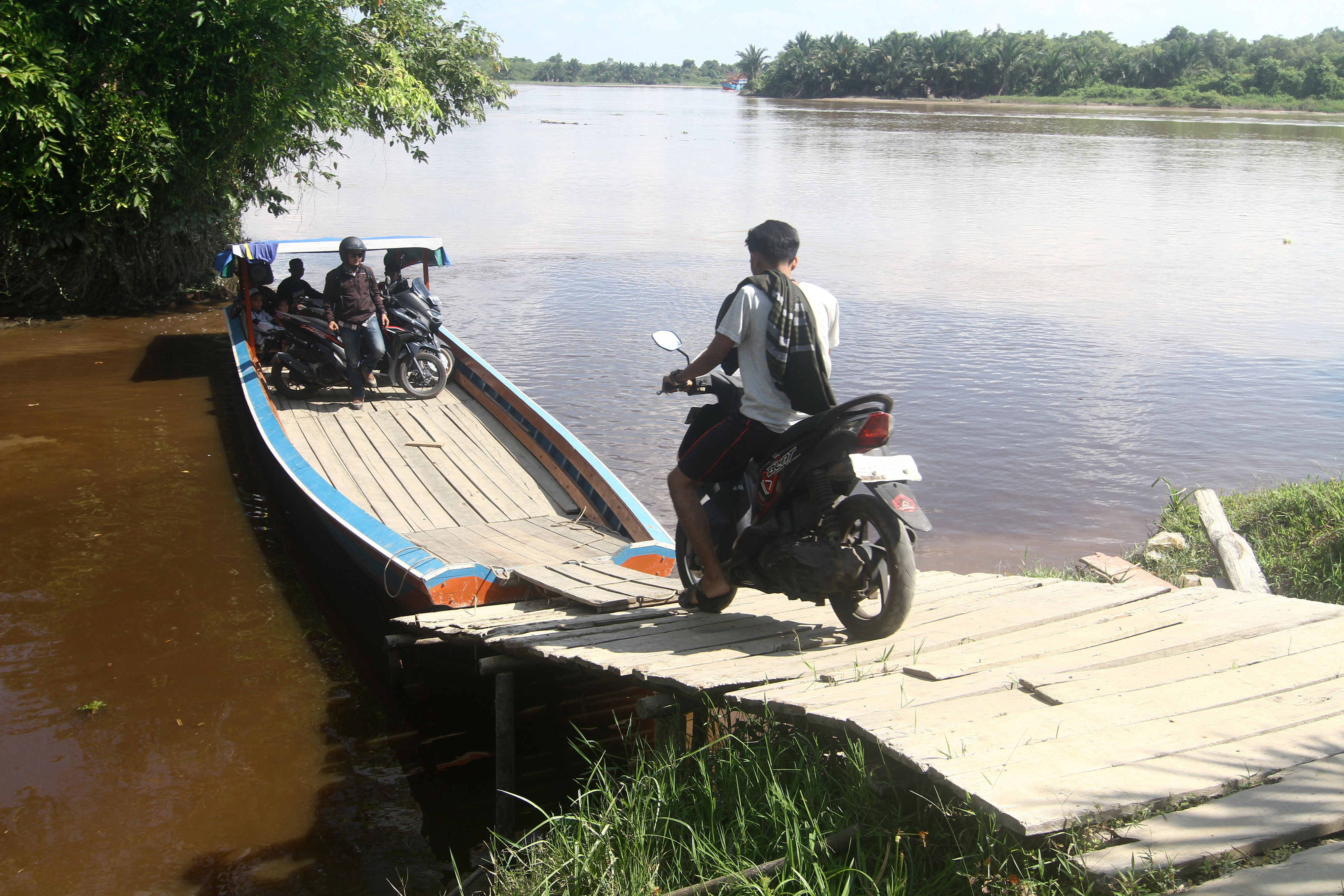 Kendaraan penumpang ke atas kapal motor untuk menyeberangi sungai di Kecamatan Sungai Raya, Kabupaten Kubu Raya, Kalbar, Minggu (25/7/2021)