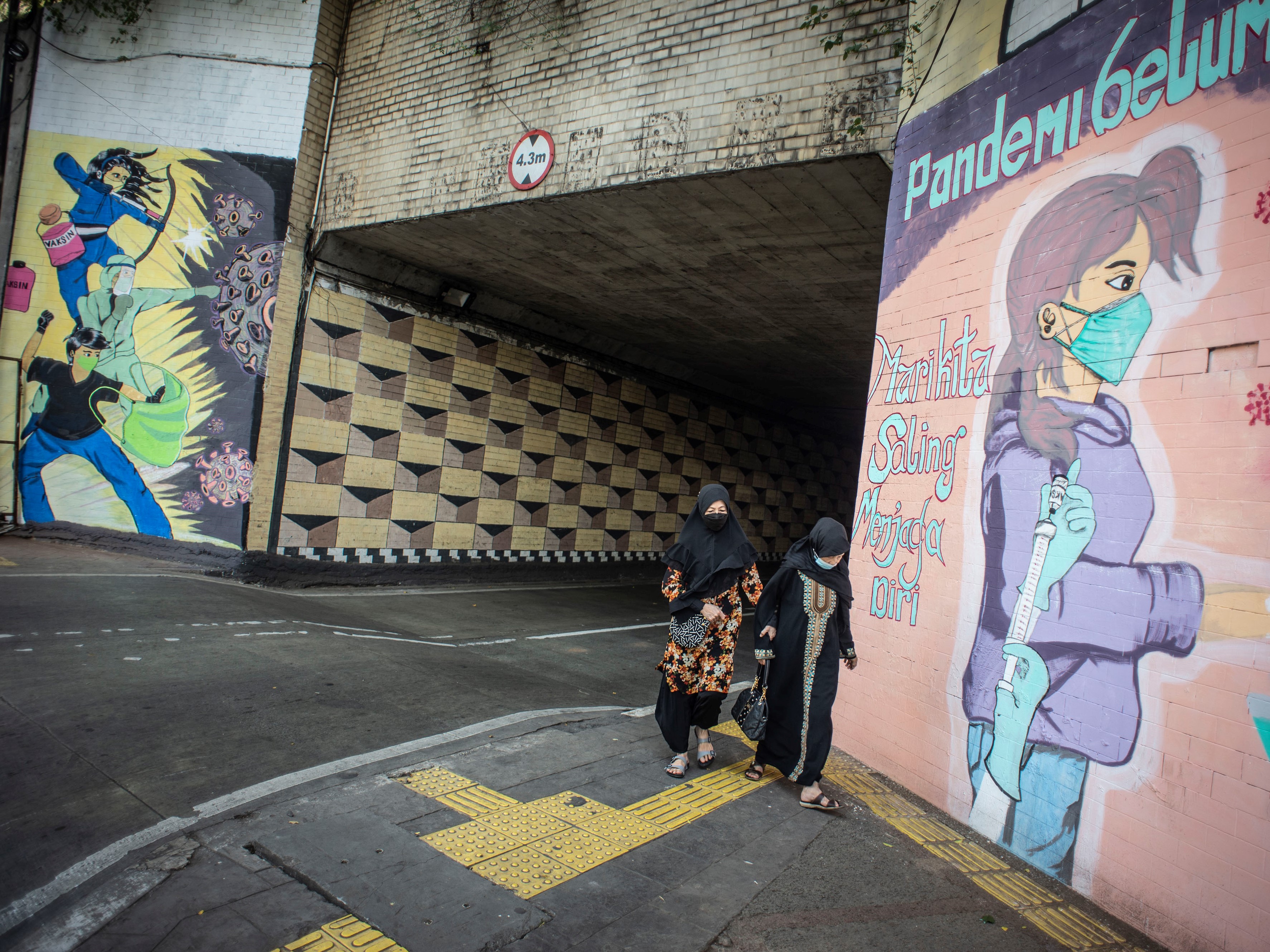 Warga berjalan di dekat mural bertema pencegahan penyebaran covid-19 di Jakarta, Rabu (28/7).