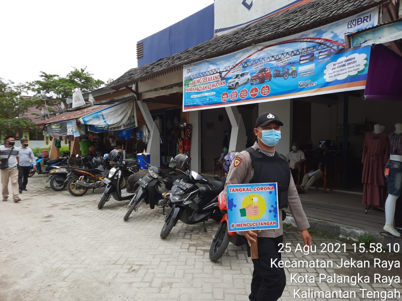 Seorang petugas Polresta Palangka Raya berkeliling pasar sambil membawa papan sosialisasi di tangan