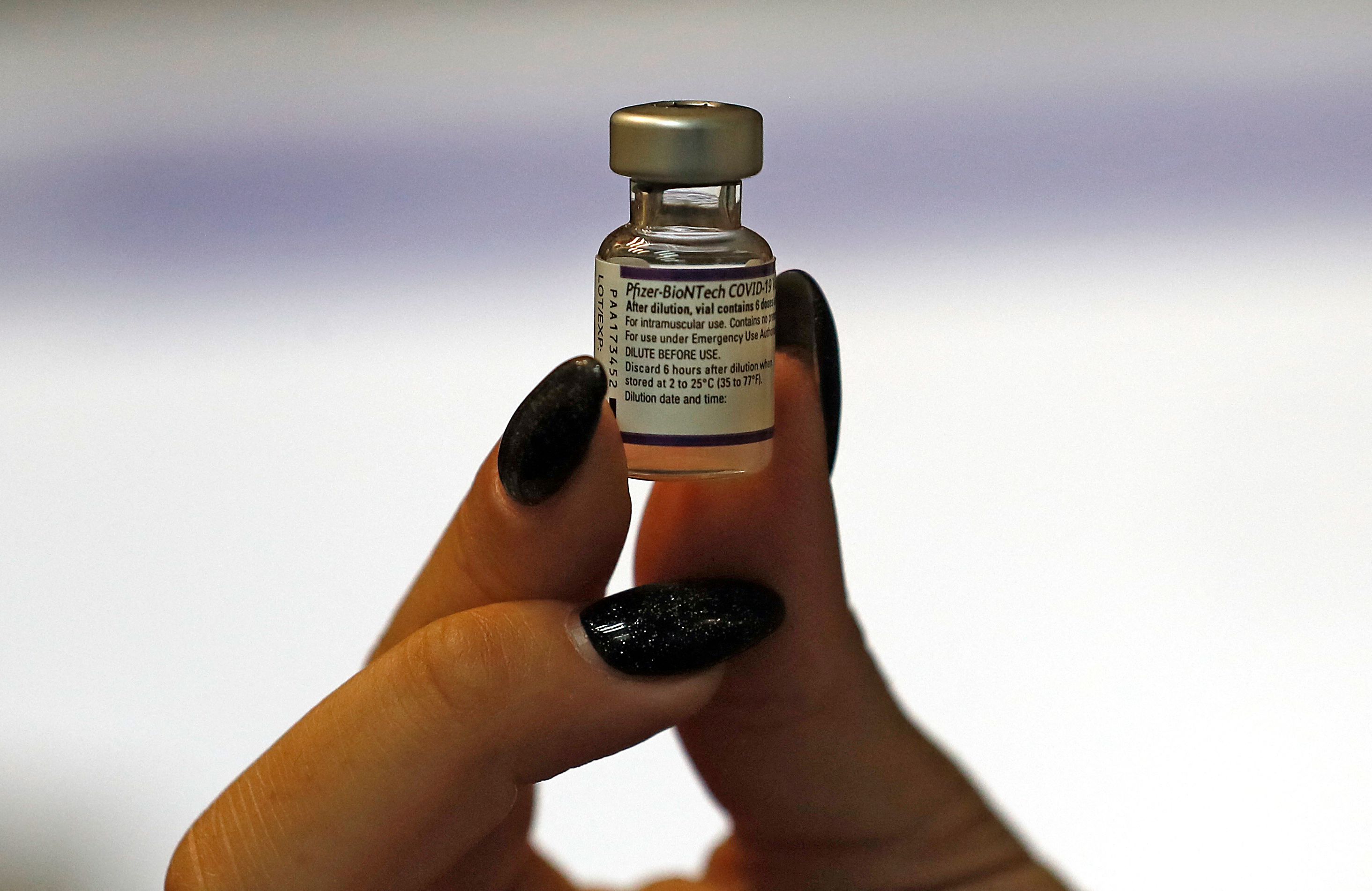 Seorang tenaga kesehatan memperlihatkan botol berisi vaksin covid-19 buatan Pfizer-BioNTech.