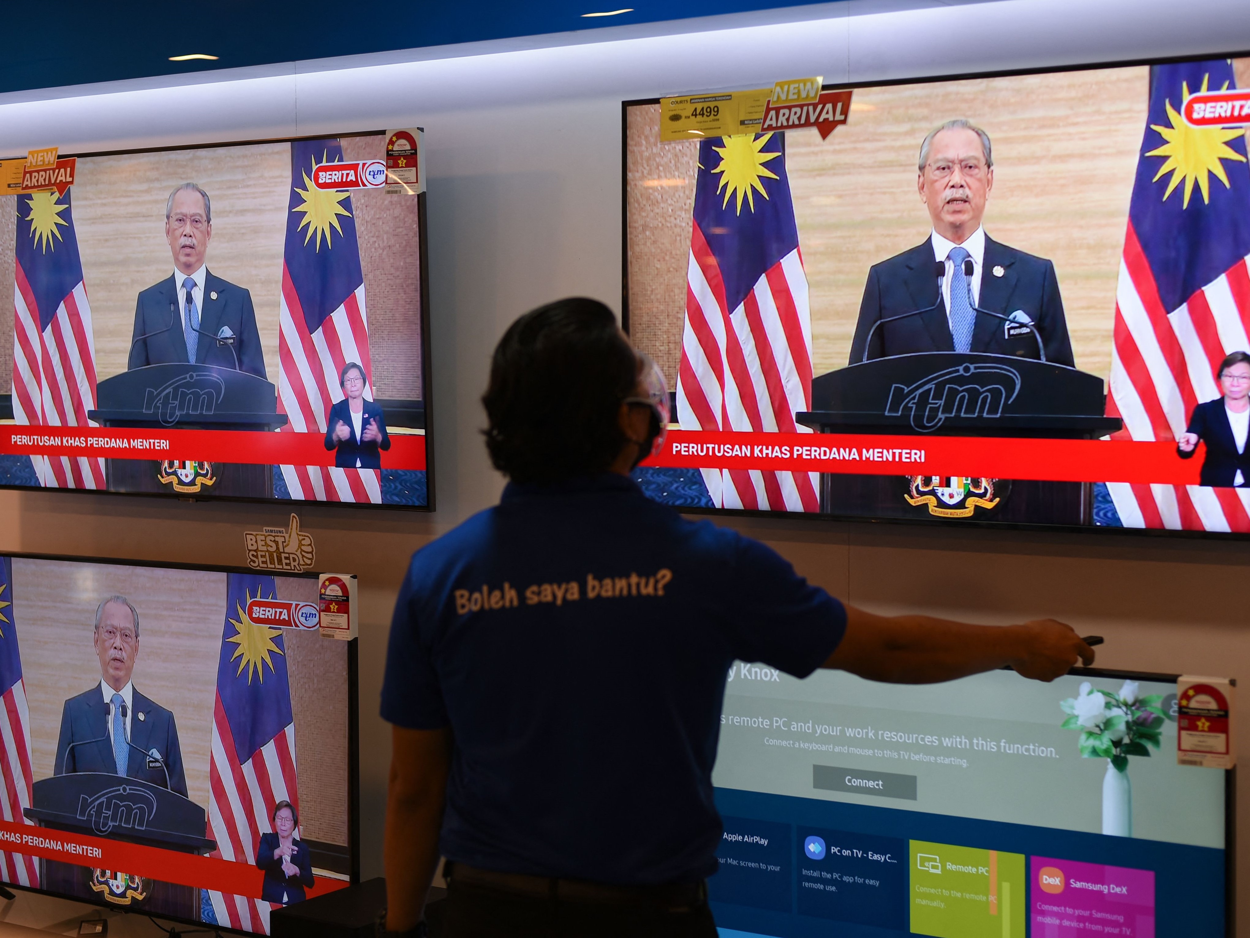 Seorang pria menonton televisi yang dipajang toko ketika PM Malaysia Muhyiddin Yassin mengumumkan pengunduran diri.