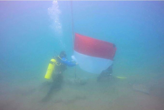 Penyelam mengibarkan bendera merah putih dari dasar laut perairan Pantai Ujong Batee, Kecamatan Muara Dua, Kota Lhokseumawe, Selasa (17/8).