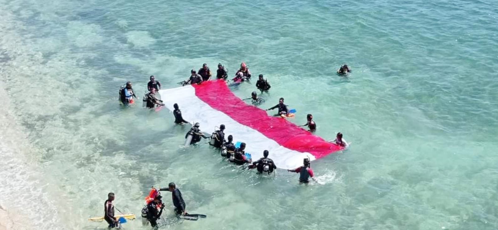 Para penyelam bersiap mengibarkan bendera Merah Putih di pantai Laut Kajuwulu di Desa Magepanda, Kecamatan Magepanda, NTT.