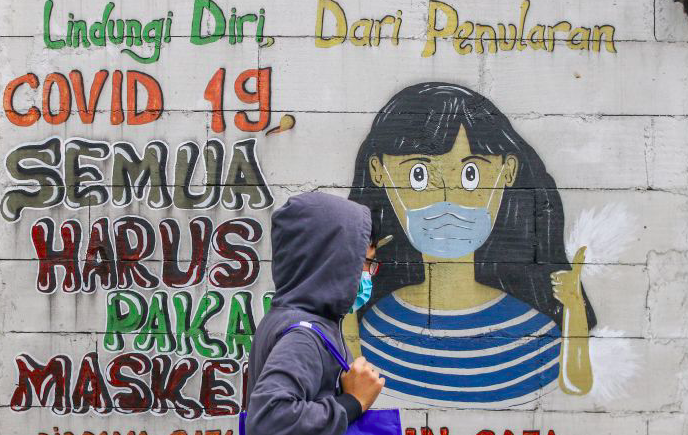 Warga melintas di dekat mural bertemakan COVID-19 di Petamburan, Jakarta.