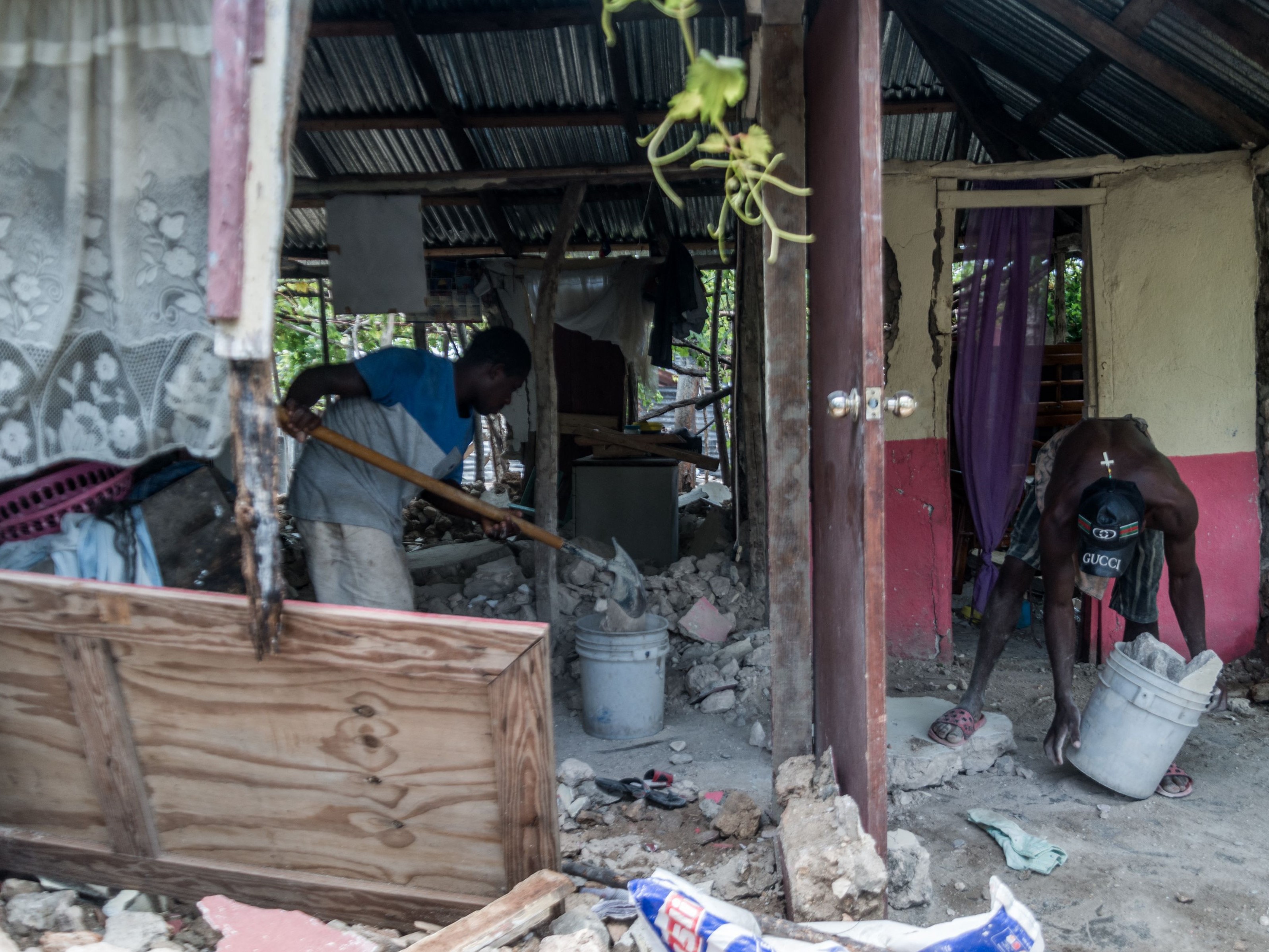 Dua pemuda membersihkan rumah yang rusak parah akibat gempa di Chardonnieres, Haiti, Rabu (18/8).